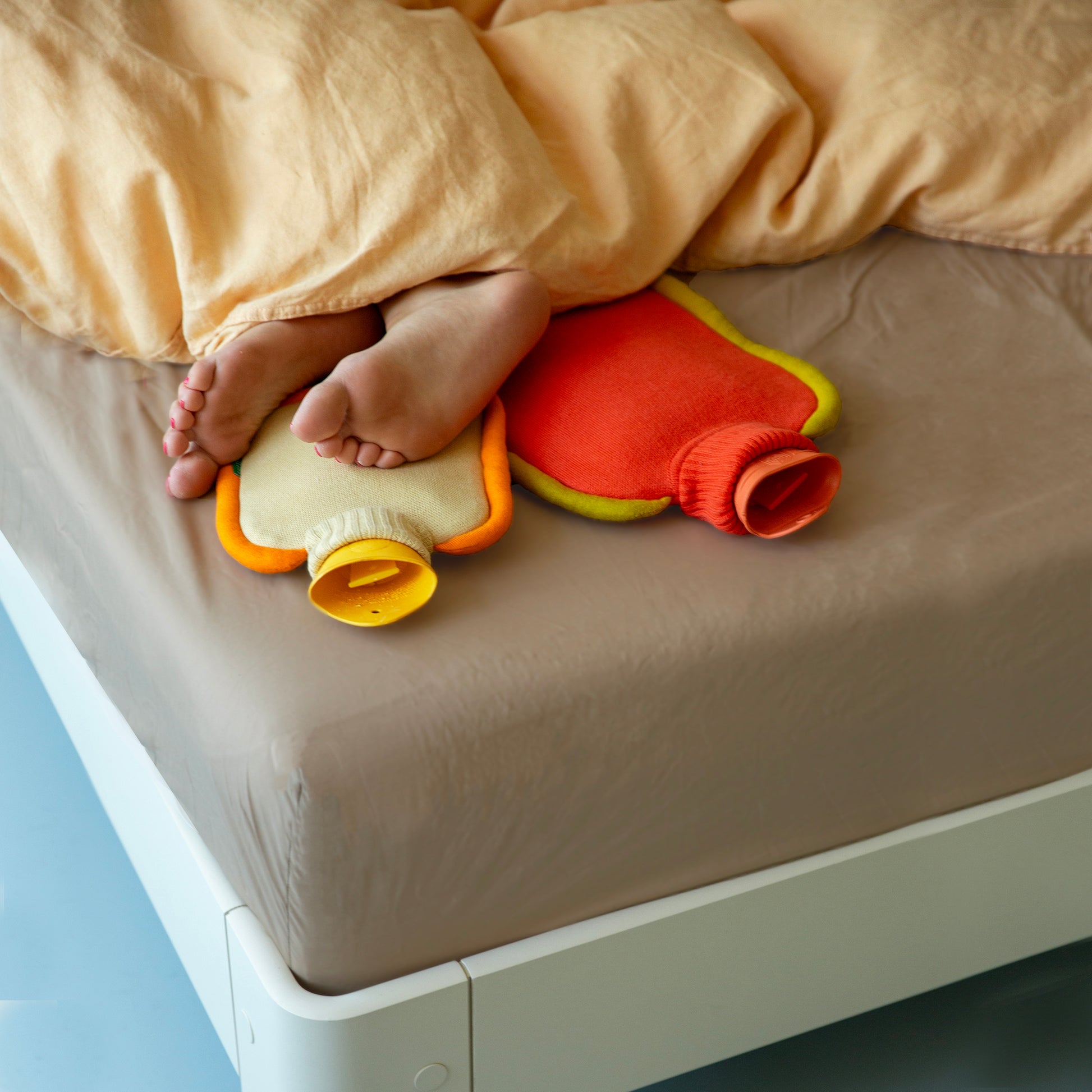 Warmwaterkruik Katoen Bumper Poppy Orange│Suite702│art. BHWBPO│met mini versie op bed met blote voeten