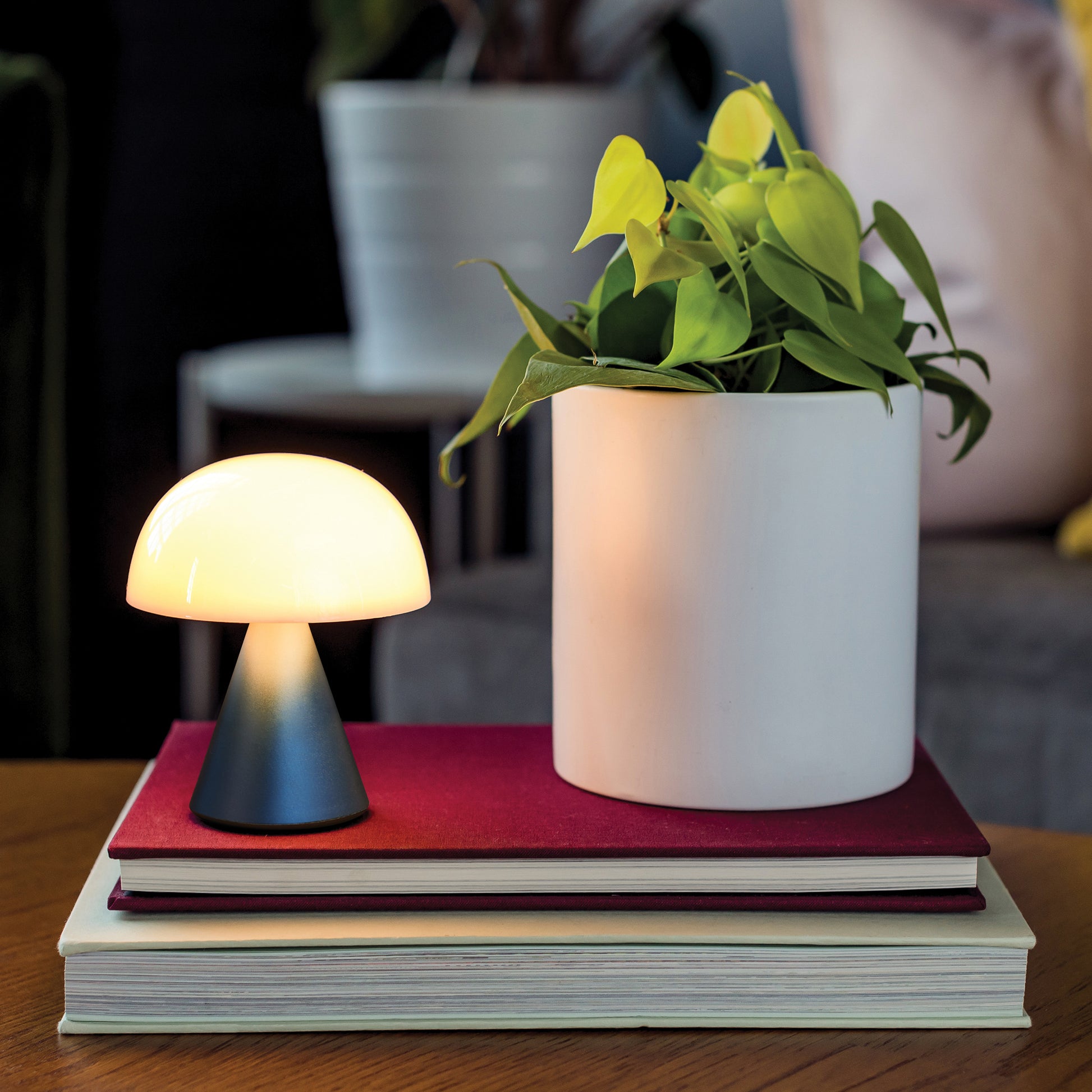 Lexon Mina Medium Donkerblauw│Oplaadbare LED-lamp│art. LH64MDB│op boeken naast plant