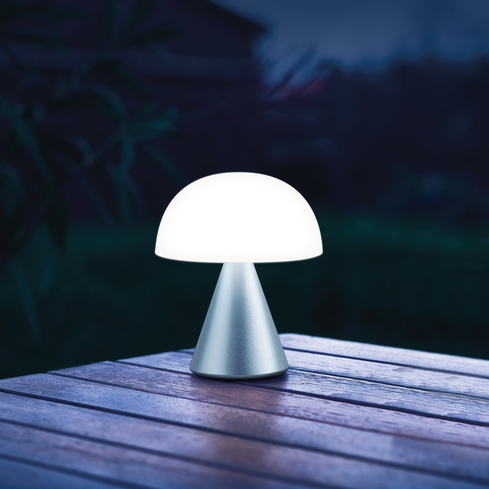 Lexon Mina Medium Donkerblauw│Oplaadbare LED-lamp│art. LH64MDB│op buitentafel met wit licht aan