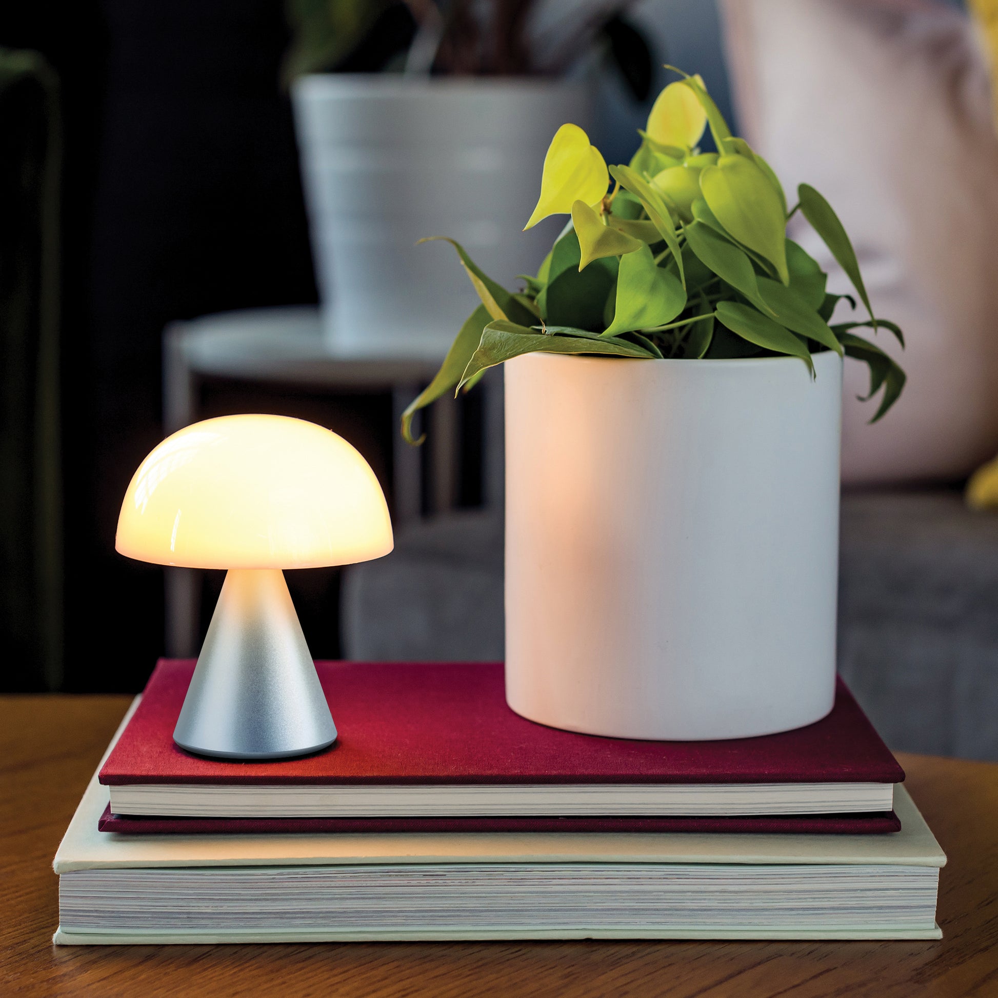 Lexon Mina Medium Donkerblauw│Oplaadbare LED-lamp│art. LH64MDB│op boeken naast plant