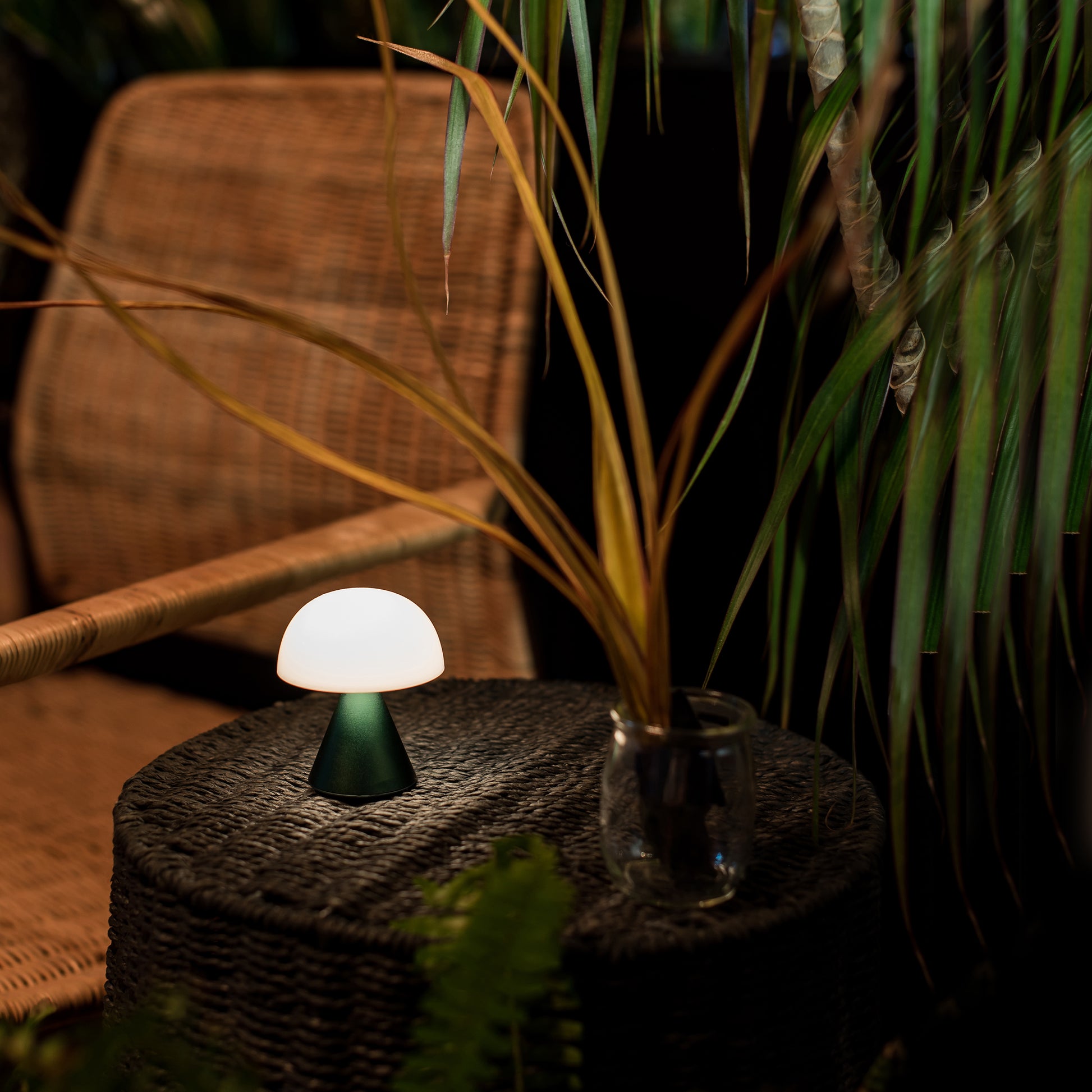 Lexon Mina Small Oplaadbare LED-Lamp Donkergroen│art. LH60DG1│buiten op rieten tafeltje met licht aan
