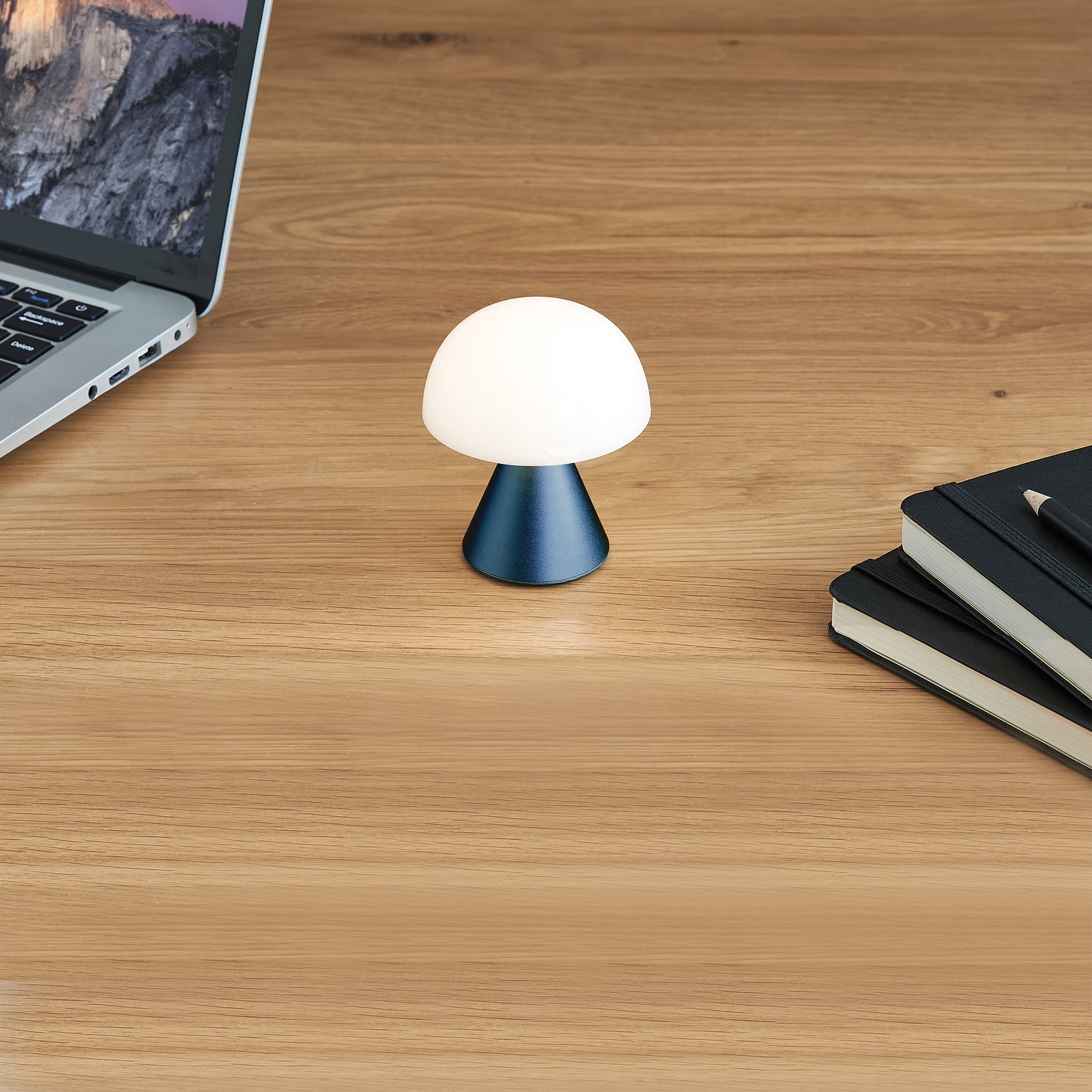 Lexon Mina Small Donkerblauw│Oplaadbare LED-Lamp│art. LH60MDB│op houten tafel naast laptop