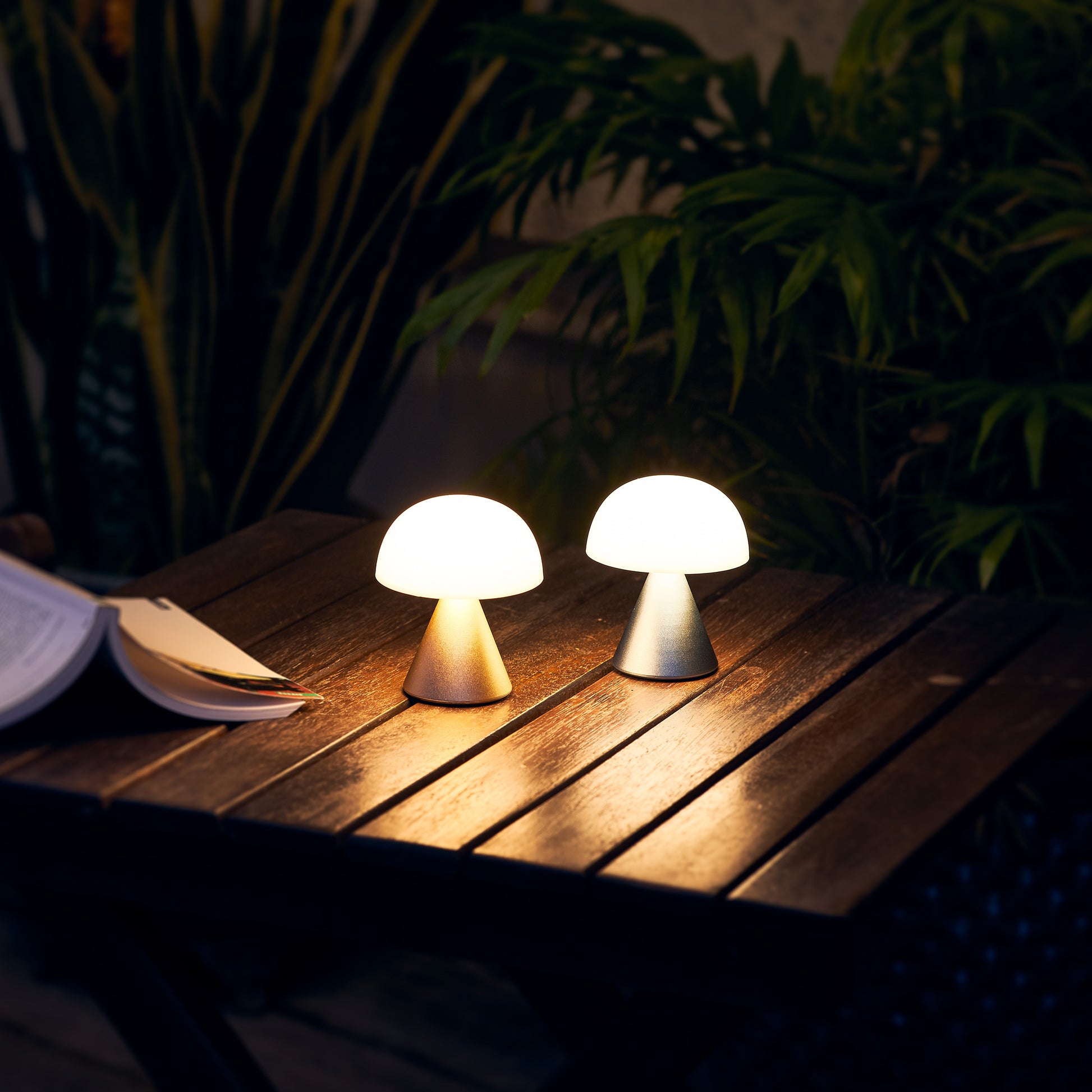 Lexon Mina Small Aluminium│Oplaadbare LED-Lamp│art. LH60MAP│met gouden versie op houten buitentafeltje naast boek