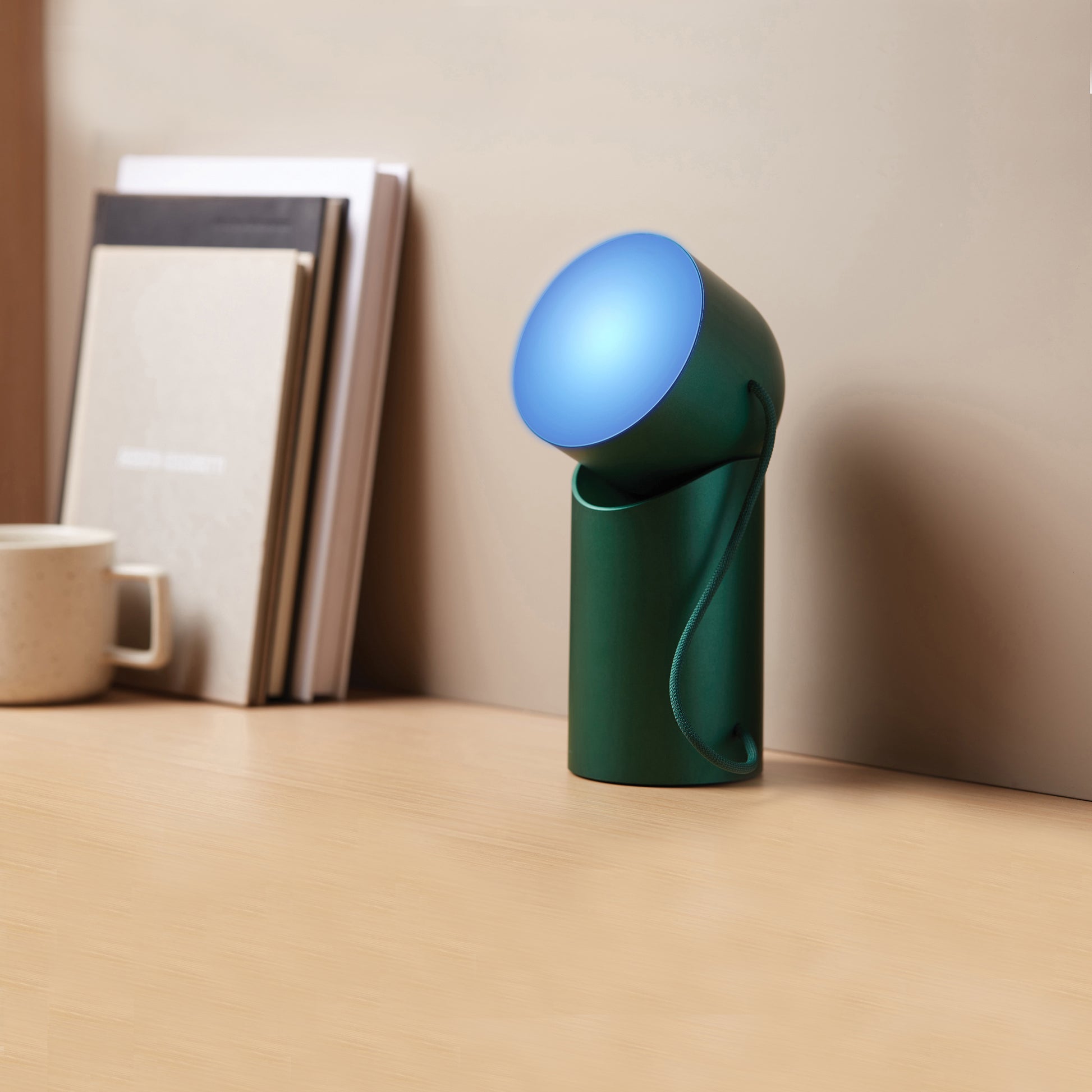Lexon Orbe Donkergroen│Oplaadbare Tafellamp│art. LH88DG1│op bureau met blauw licht aan