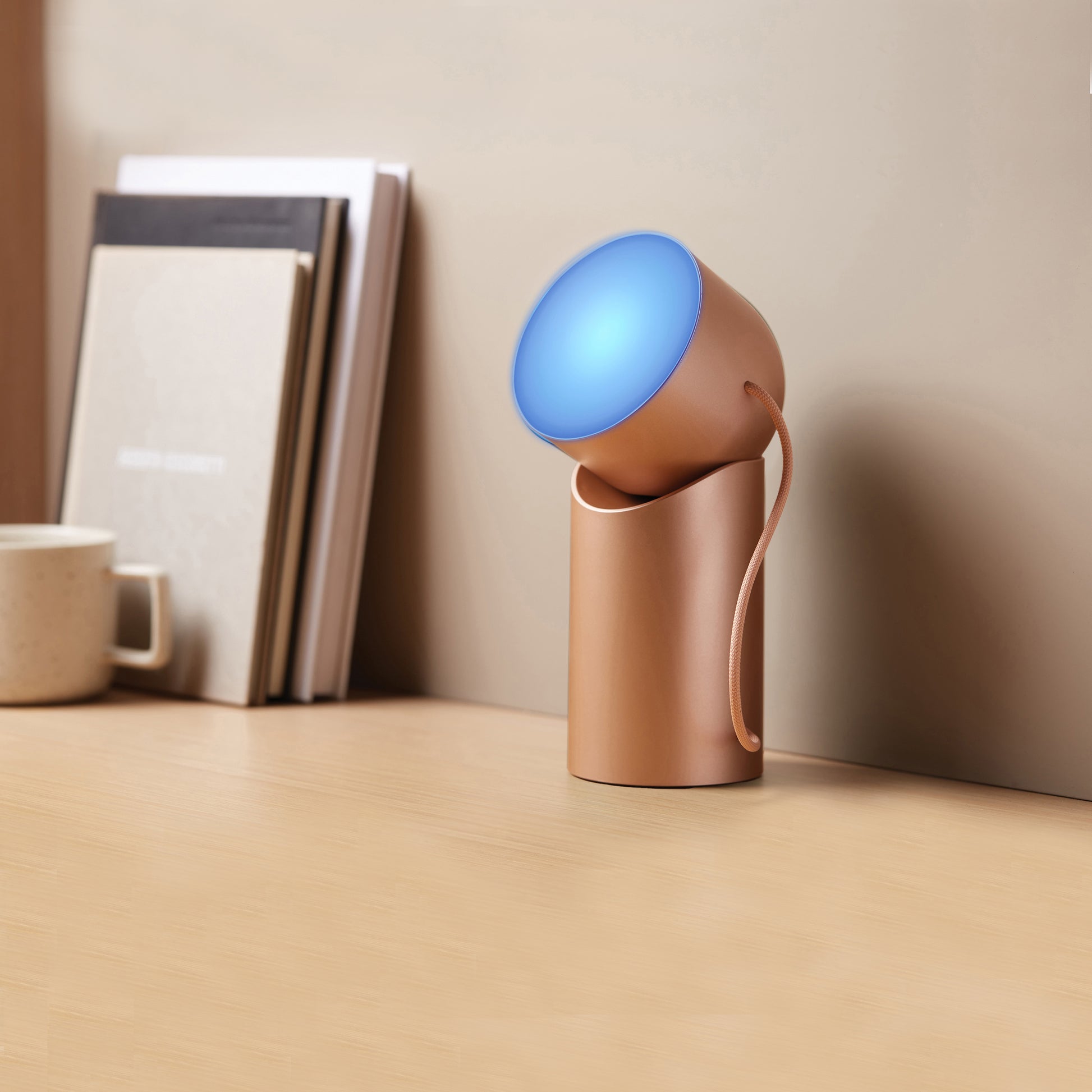 Lexon Orbe Goud│ Oplaadbare Tafellamp│art. LH88D│op bureau met blauw licht aan