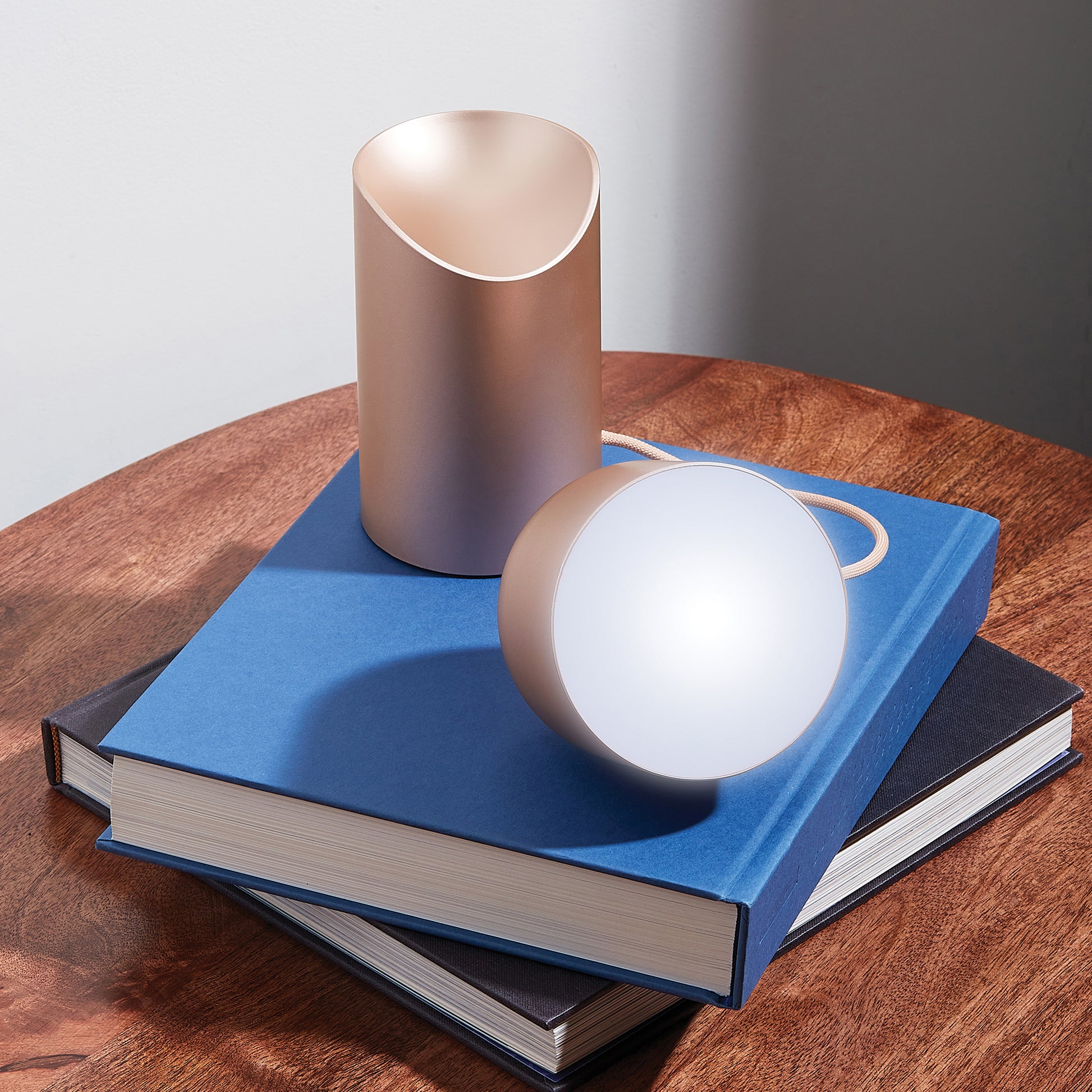 Lexon Orbe Goud│ Oplaadbare Tafellamp│art. LH88D│op boeken met lamphoofd los naast basis