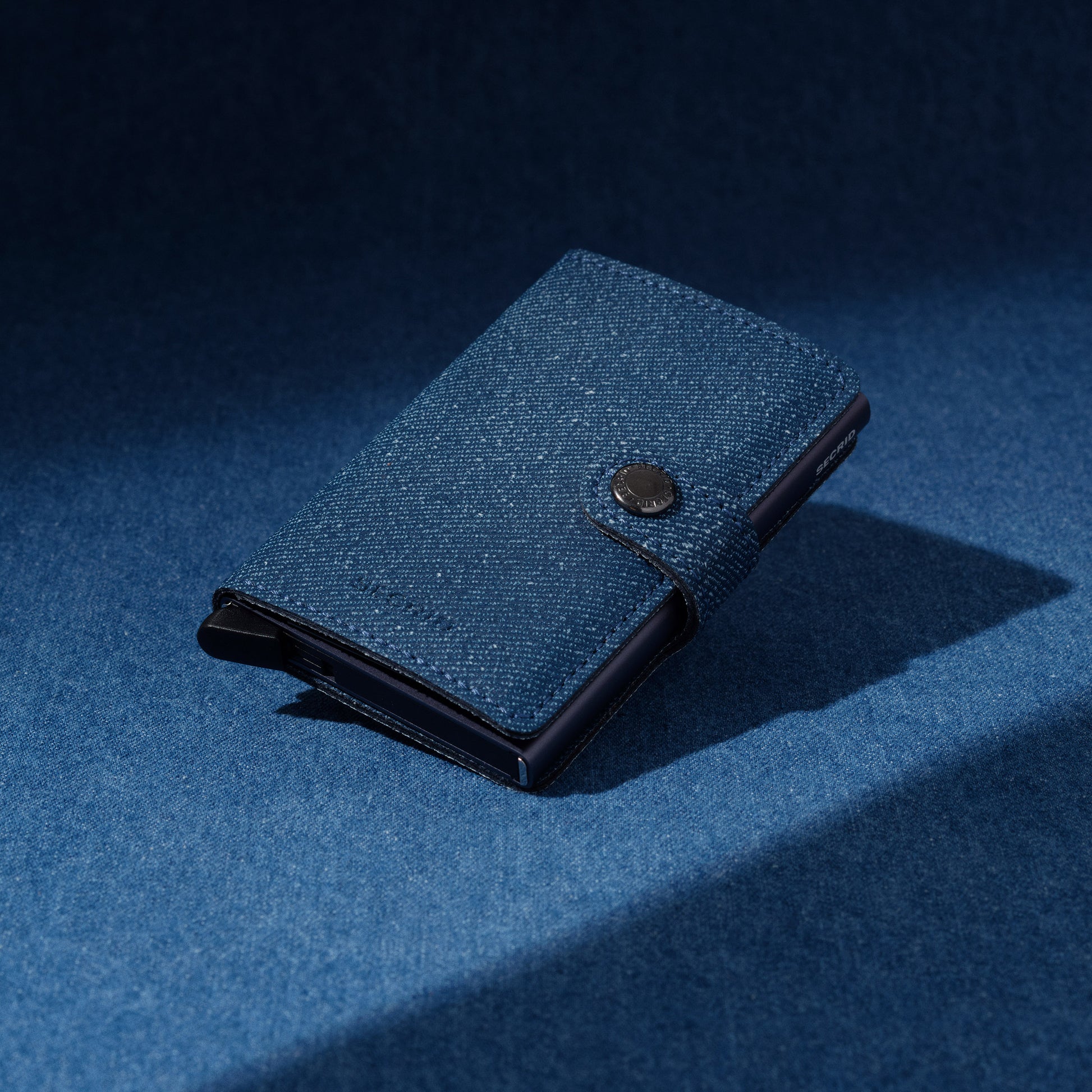 Secrid Miniwallet Twist│art. MTW-JEANS-BLUE││Pasjeshouder│schuin liggend op spijkerstof