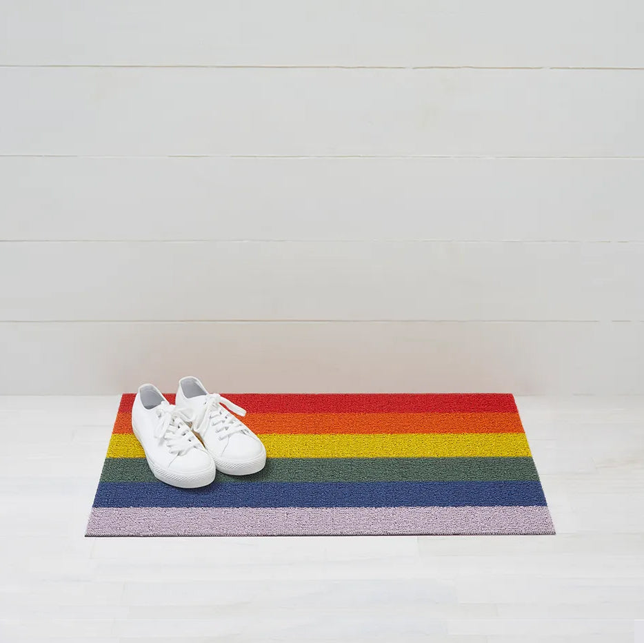 Chilewich Shag Deurmat 46x71 Pride Rainbow│art. 200872-001│met witte gymschoenen op houten vloer