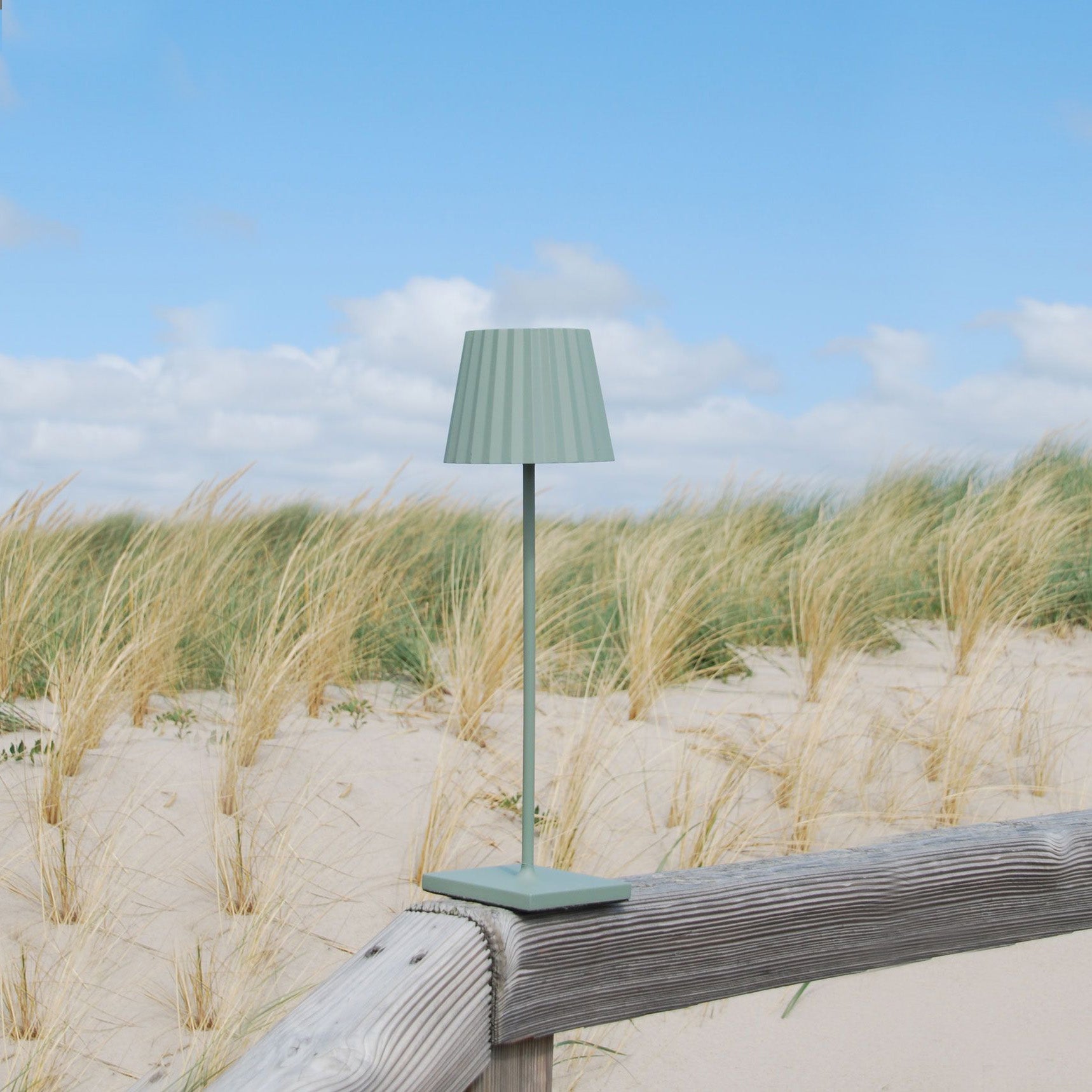 Sompex Troll 2.0 Olijfgroen│Oplaadbare Tafellamp│Buitenverlichting│art. 78174│op houten hek in duinen