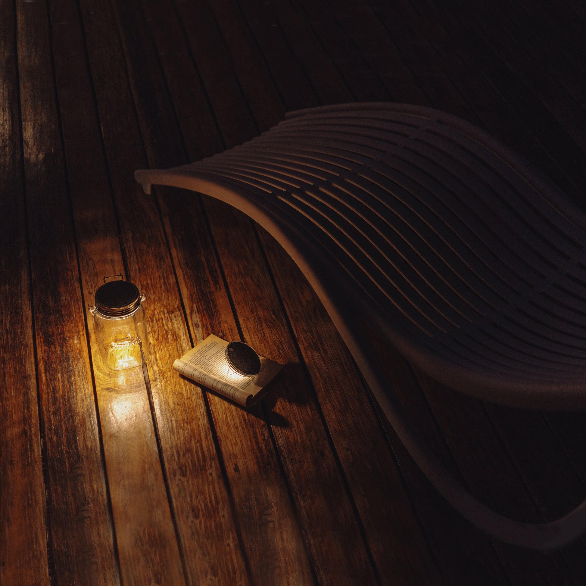 Sonnenglas Classic Gen6│Licht in een Glazen Pot│oplaadbare lantaarn op zonne-energie│op terras naast boek met licht aan