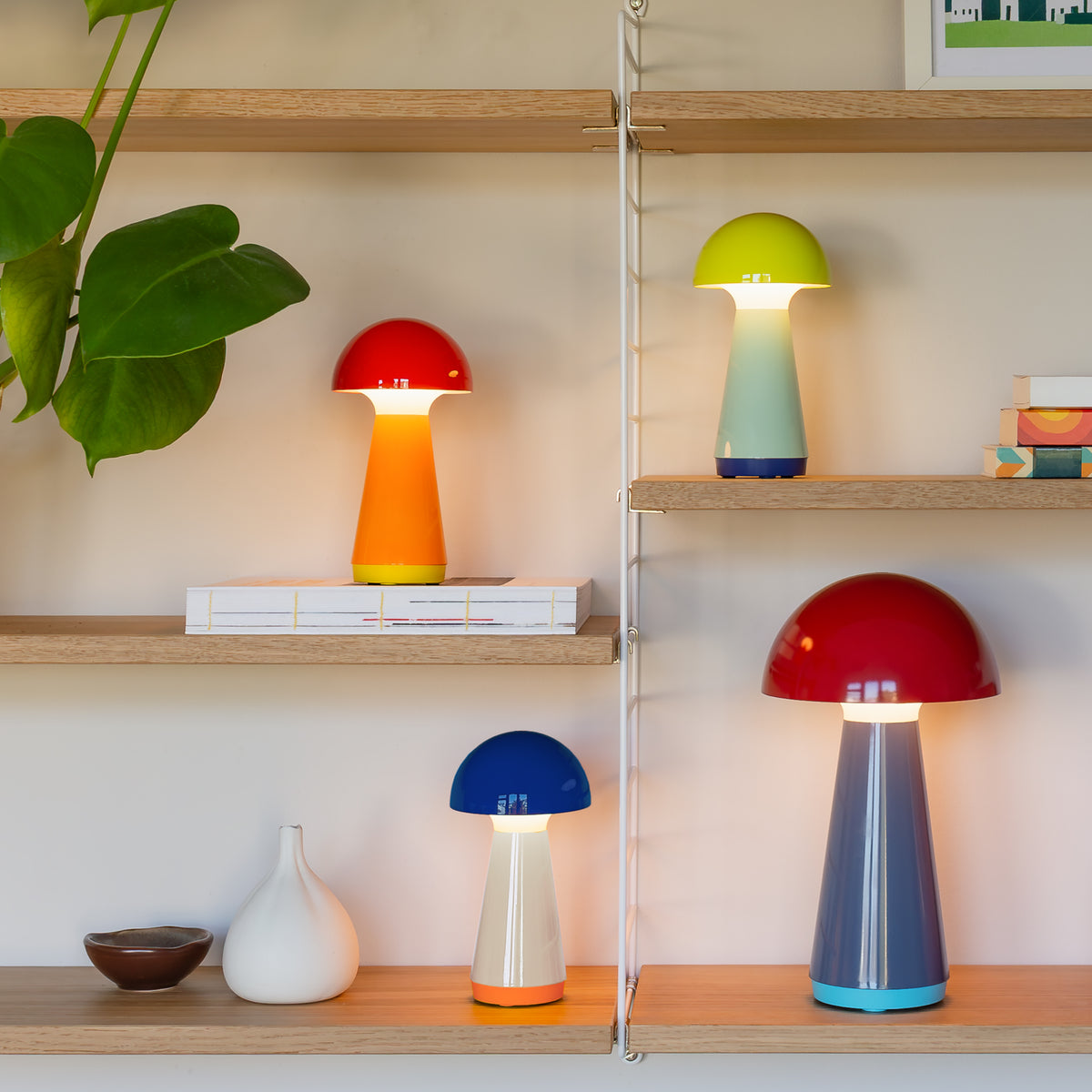 Remember Bobbi Rechargeable LED Table Lamp | in coral, blue and yellow with Bob Red on a wall shelf, light on