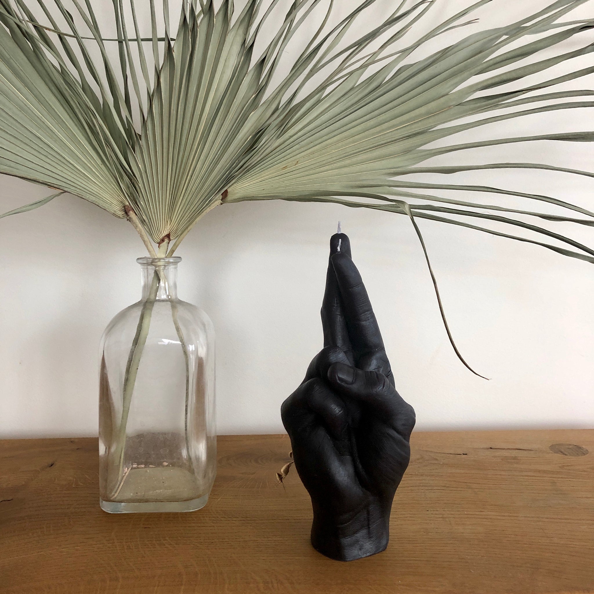 Candlehand Crossed Fingers Kaars Zwart│art. CROSS-BLACK│op houten tafel naast plant