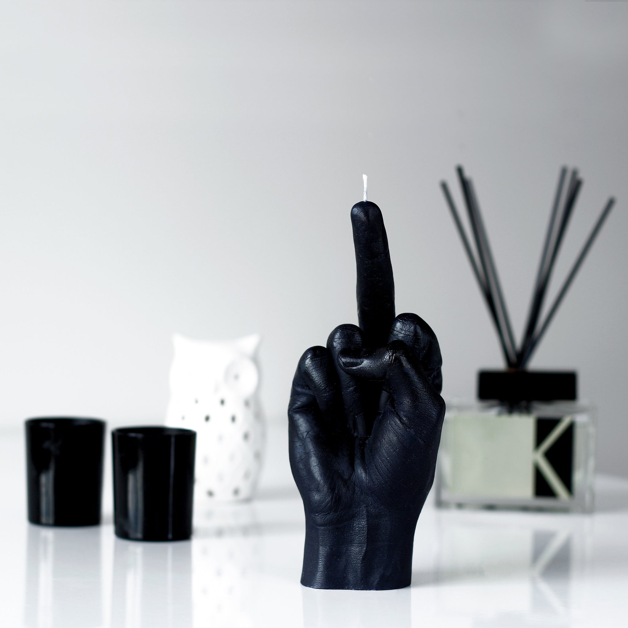 Candlehand F*ck You Kaars Zwart│art. FCK-BLACK│in setting naast diverse witte en zwarte items