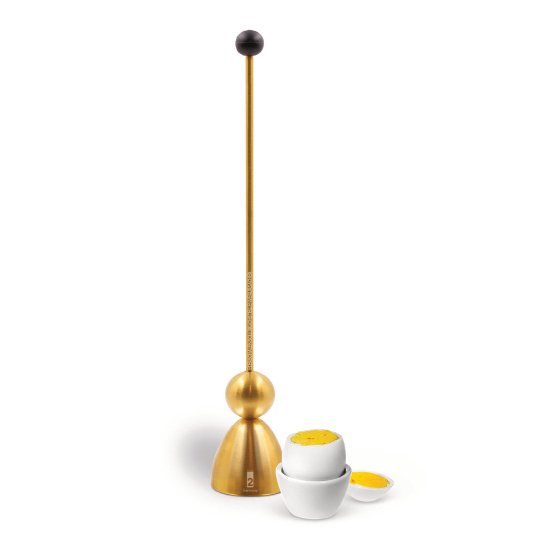 Clack egg topper in matt gold, close up with a boiled egg in an egg cup in the background.