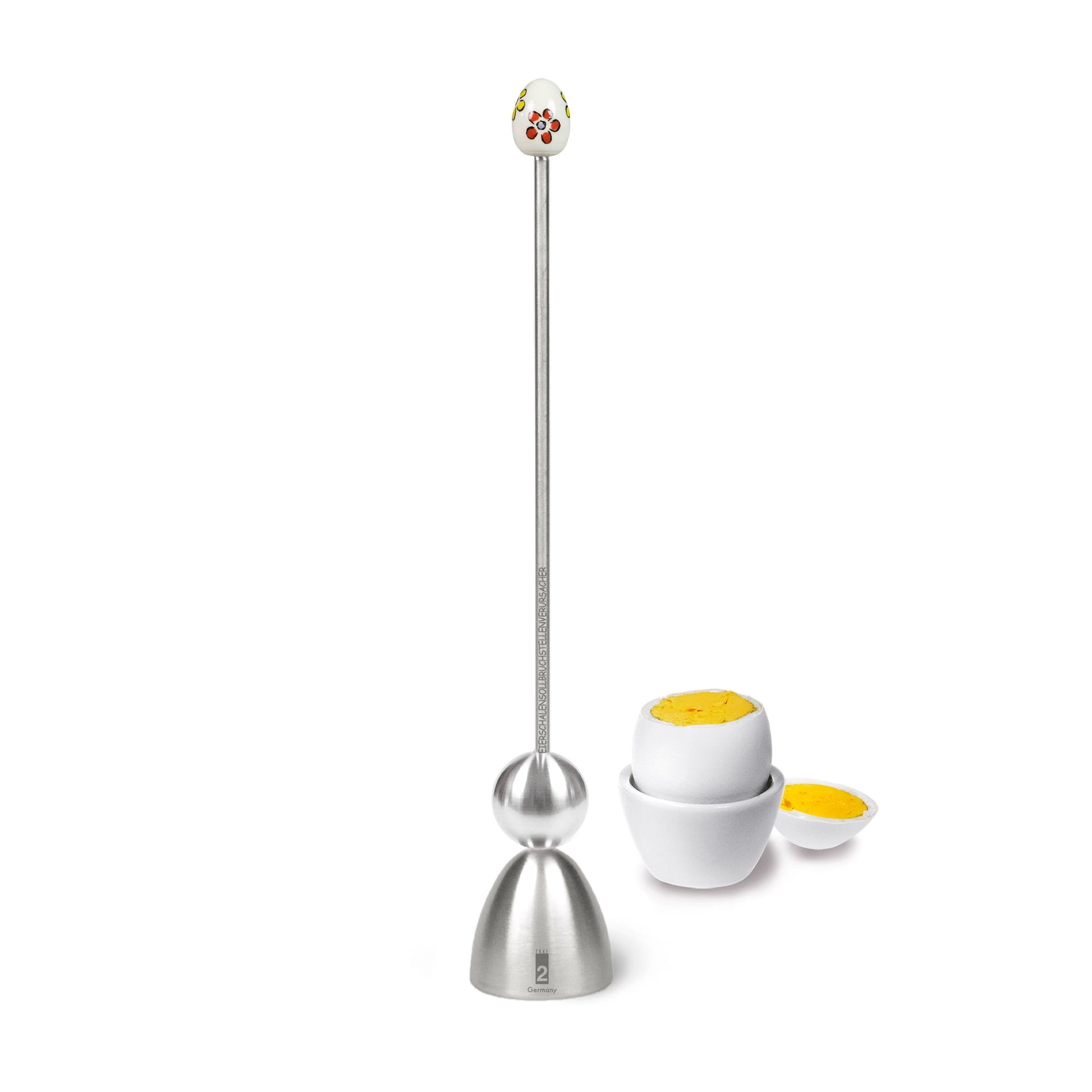 Clack Eierköpfer mit Blumen neben einem gekochten Ei im Eierbecher.