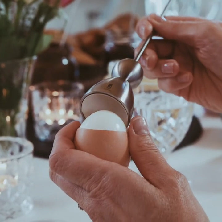 Clack egg topper with a ceramic egg with musical notes, close up beside an egg cup.