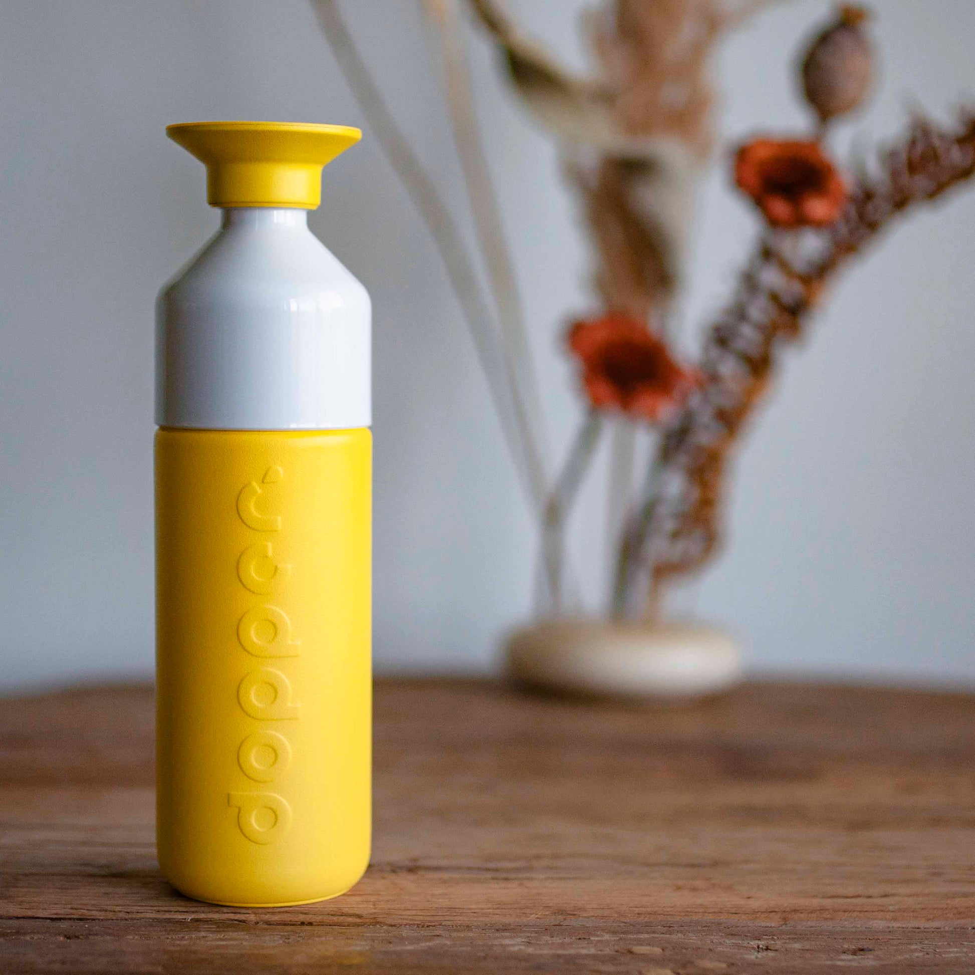 Dopper Insulated Lemon Crush│Thermosfles 580ml Geel│art. 4459│op houten tafel met bloemstuk