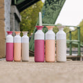 Dopper Insulated Small en large in diverse kleuren naast elkaar met ijzeren brug op achtergrond