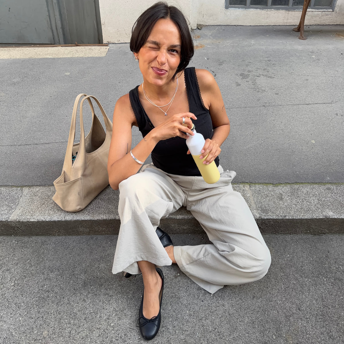 Insulated Bottle 350 ml Maple Yellow (yellow) - woman sitting on a step unscrewing the cap from the bottle