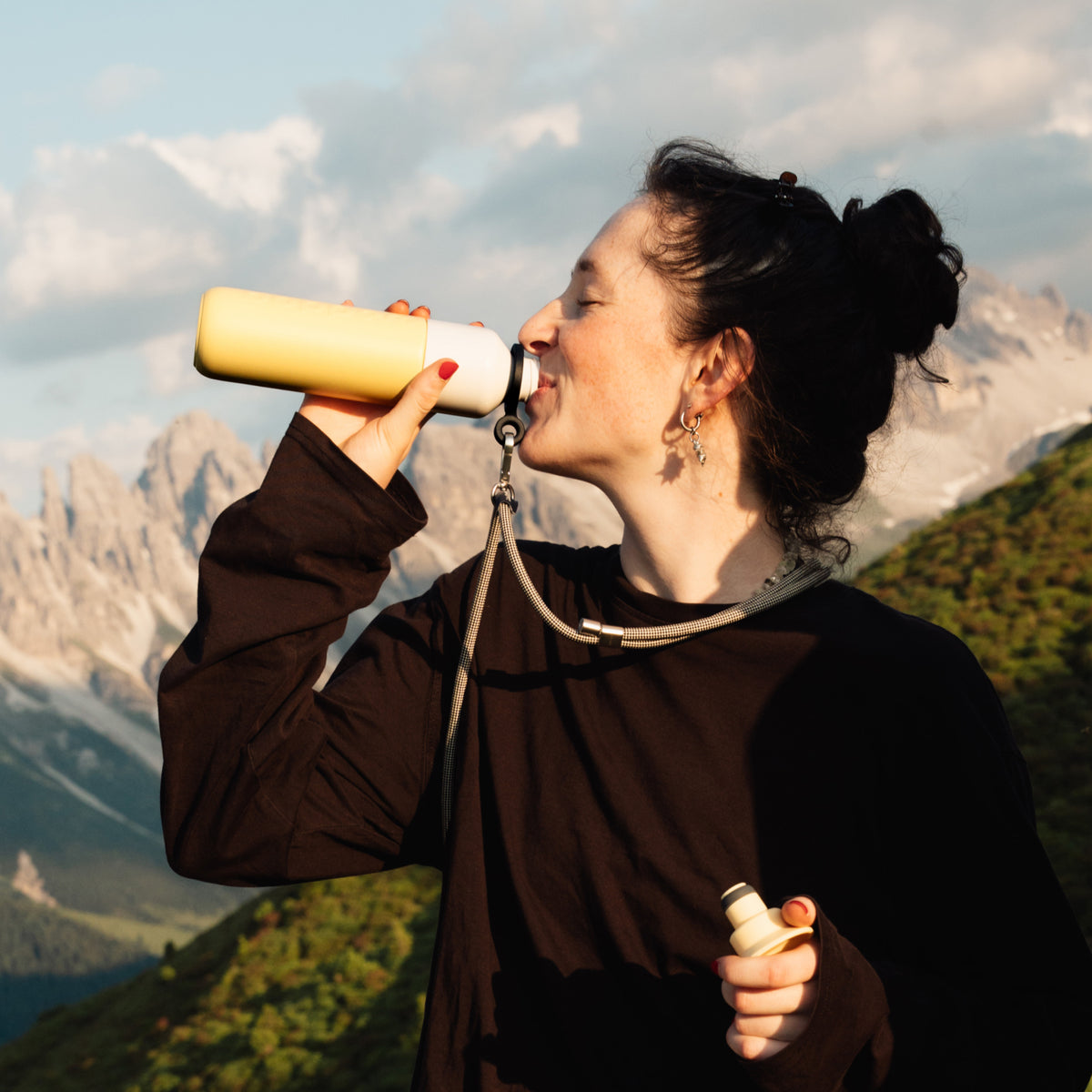 Insulated Bottle 350 ml Maple Yellow (yellow) - woman drinking from the bottle with mountains behind