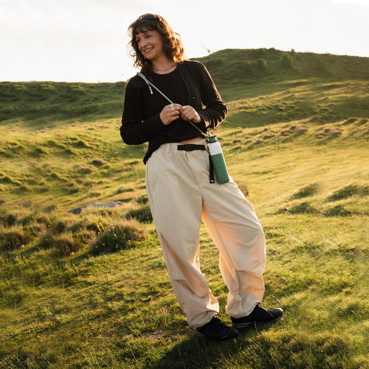 Insulated Bottle 350 ml Pine Green (green) - woman in a green landscape with the bottle on a cord over her shoulder