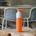Dopper Original Waterfles Outright Orange (oranje) staat op boomstronktafel met moderne eethoek op de achtergrond