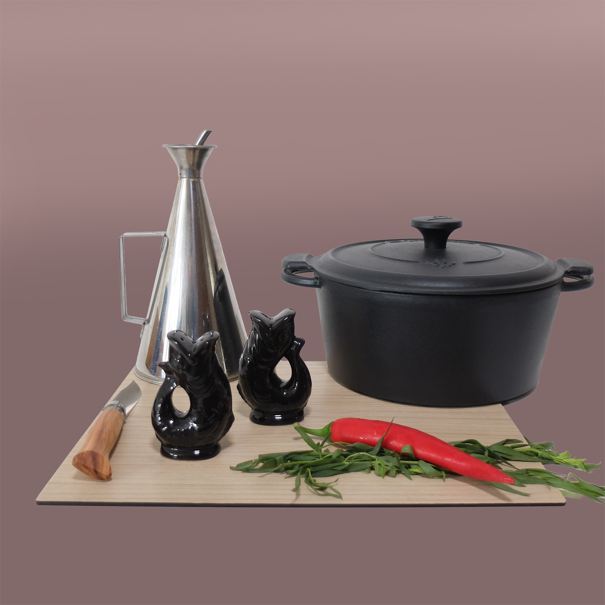Gluckigluck salt and pepper shakers in black on a chopping board beside a pan and kitchen utensils.