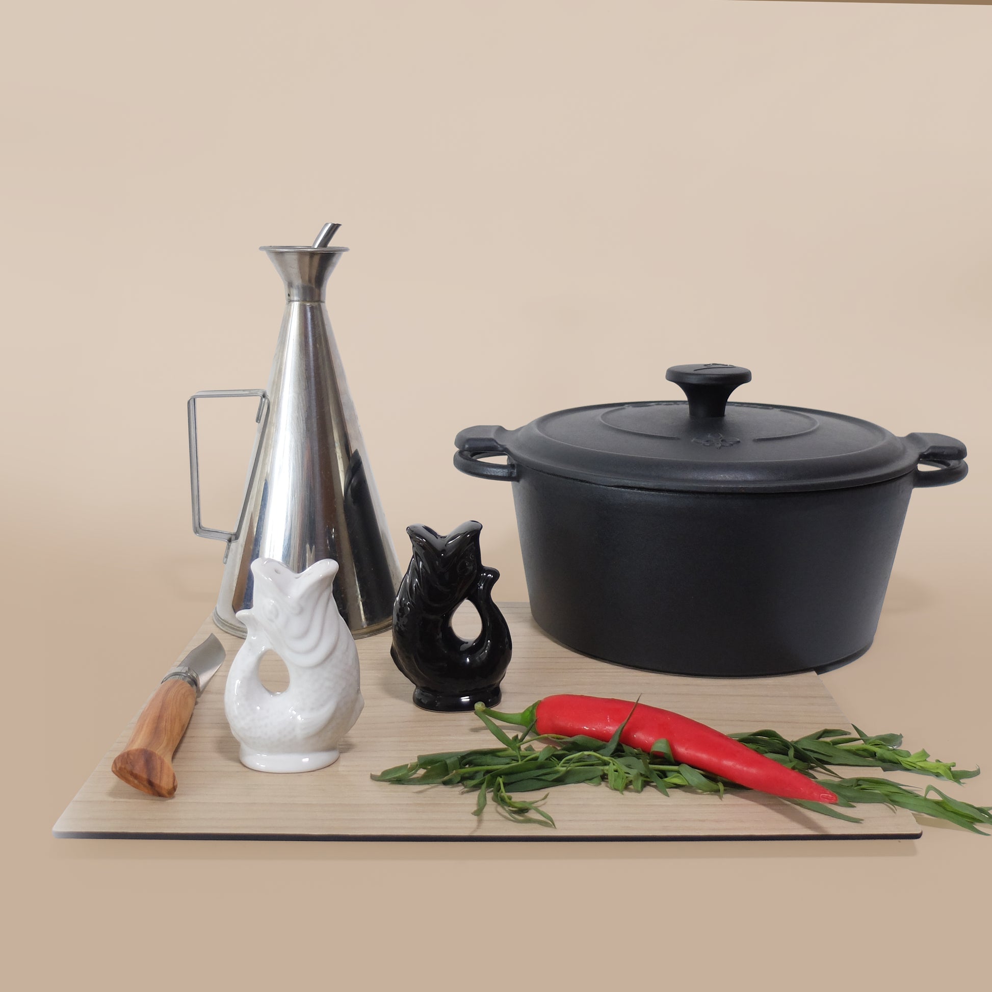 Gluckigluck salt and pepper shakers in black and white on a chopping board beside a pan and kitchen utensils.