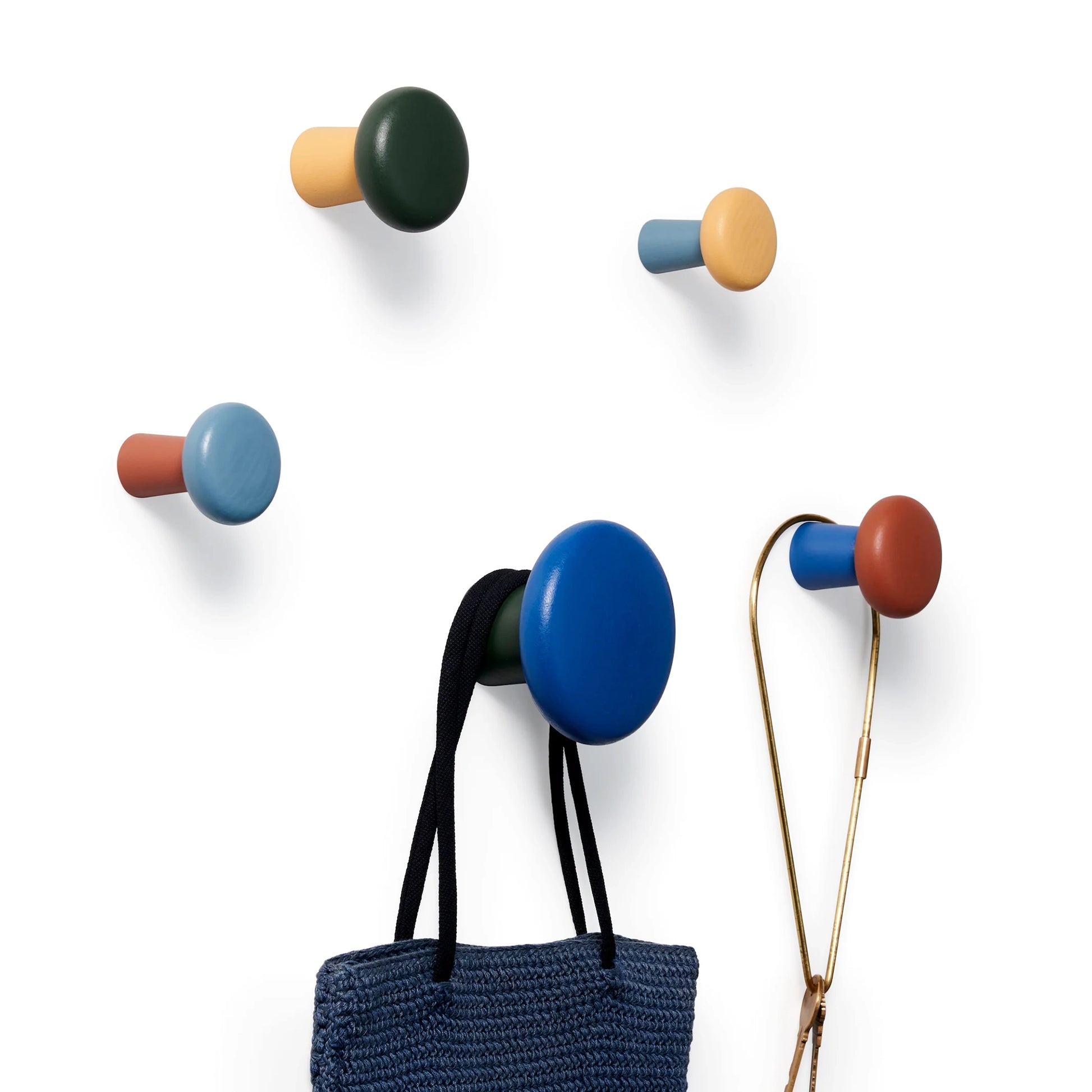 Harbor wall hooks on a white wall with a bag and a keyring hanging from them.