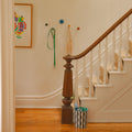 Harbor wall hooks on the wall in a hallway beside the stairs.