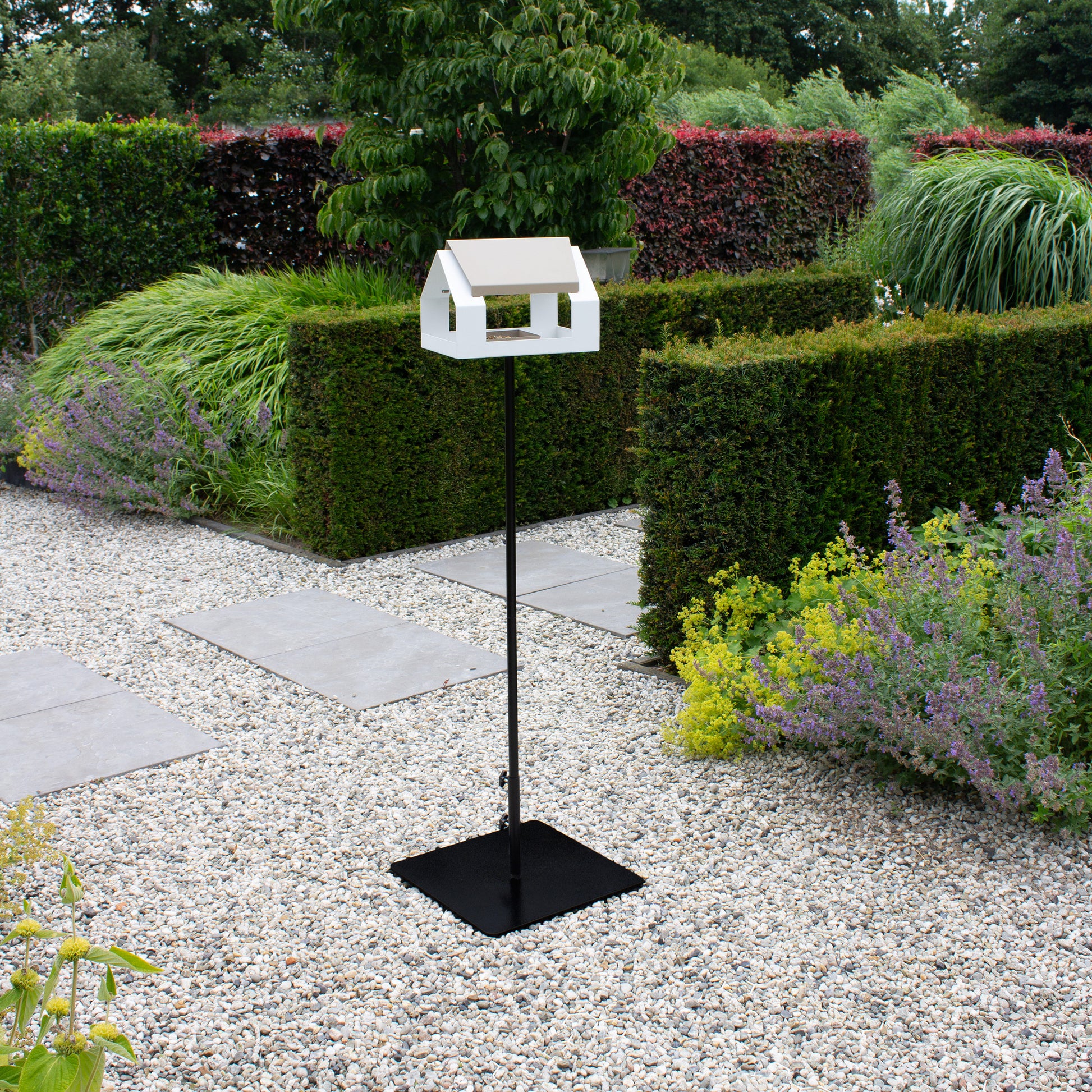 Vogelvoederhuis the Barn Wit van Heel op paal met Birdie Base op grindpad in moderne tuin