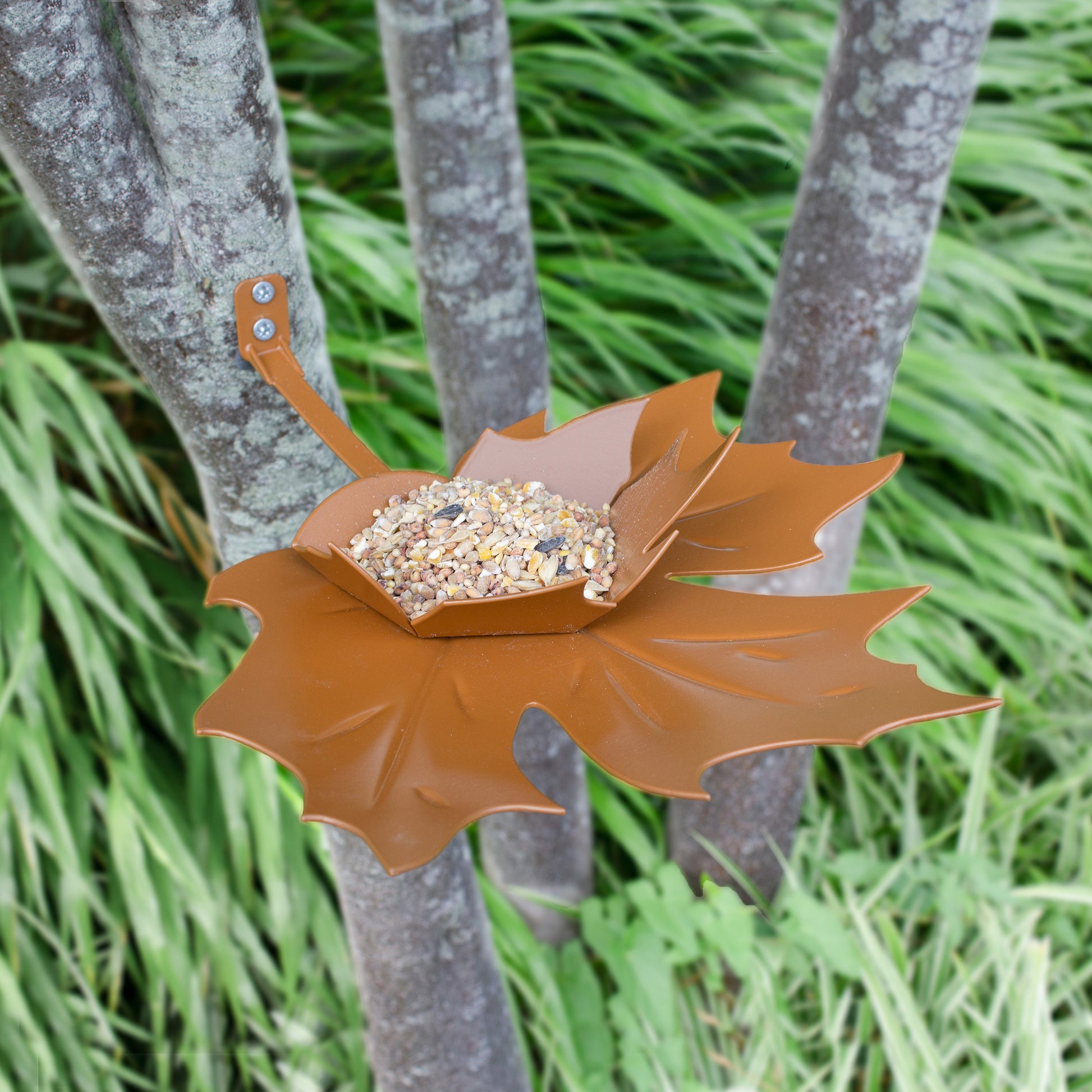 Vogelvoederschaaltje Leaf Me Bruinj hangt tegen boom met vogelzaad