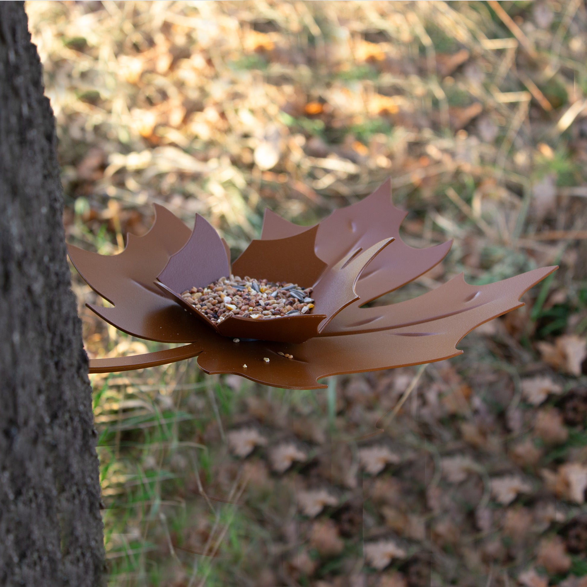 Bovenaanzicht schuin van Birdfeeder Leaf Me van Heeej met voer in schaaltje