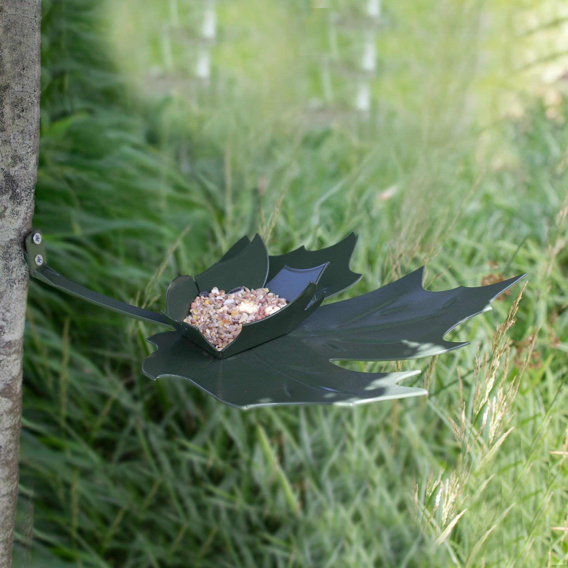 Leaf Me vogelvoerderschaal groen van Heeej tegen boom bevestigd met zaad gevuld