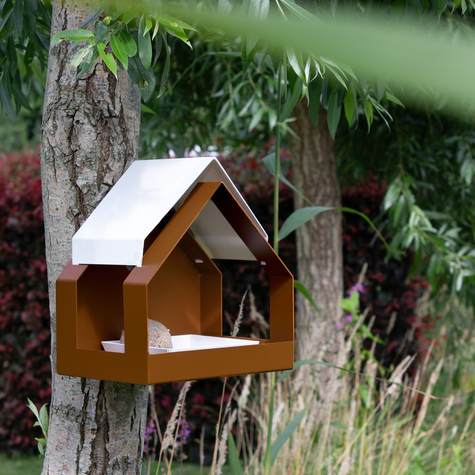The Barn Design Birdfeeder van Heeej hangt aan boom met vetbol in schaaltje