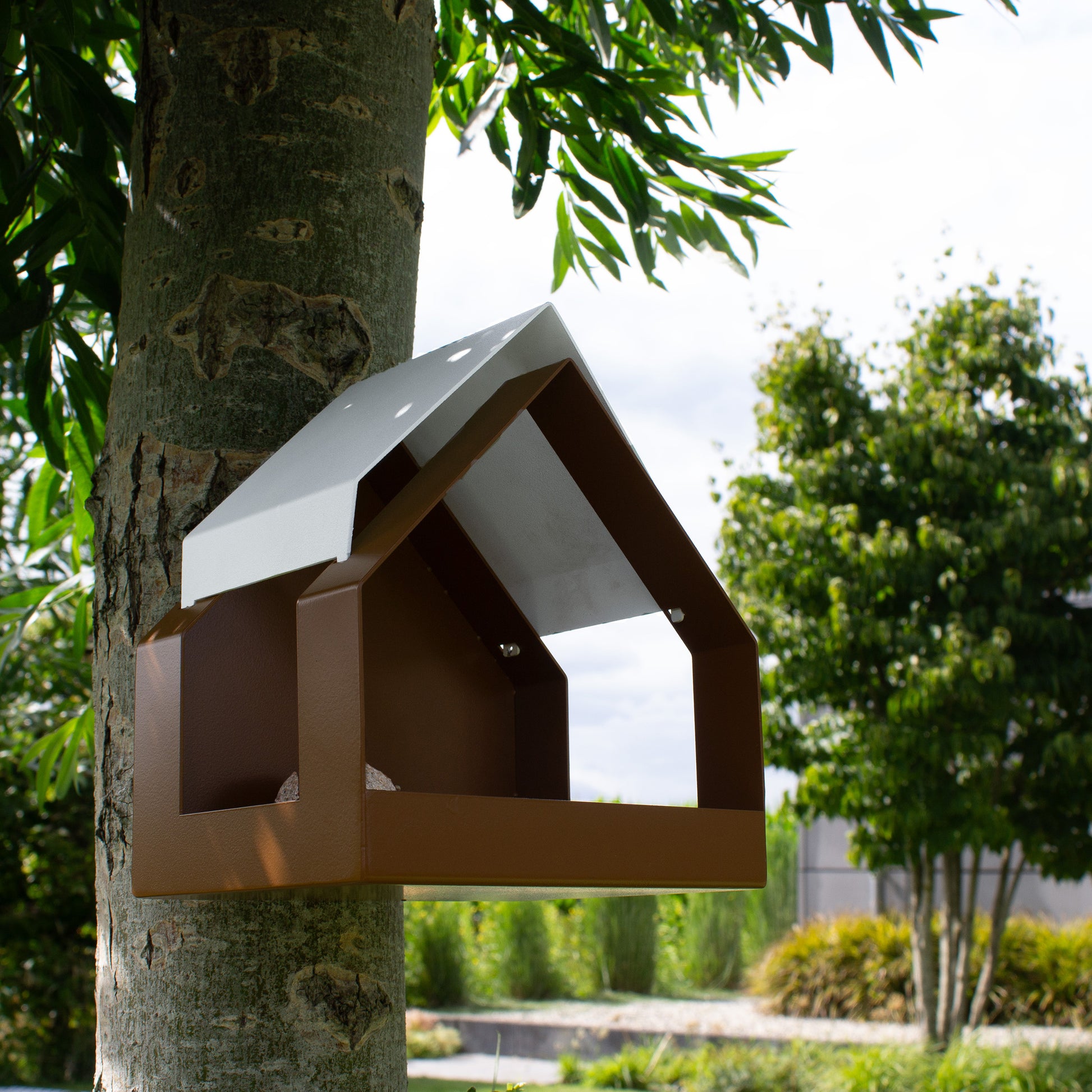 Aanzicht schuin onder van Birdfeeder the Barn in Bruin en Wit aan een boom in moderne tuin