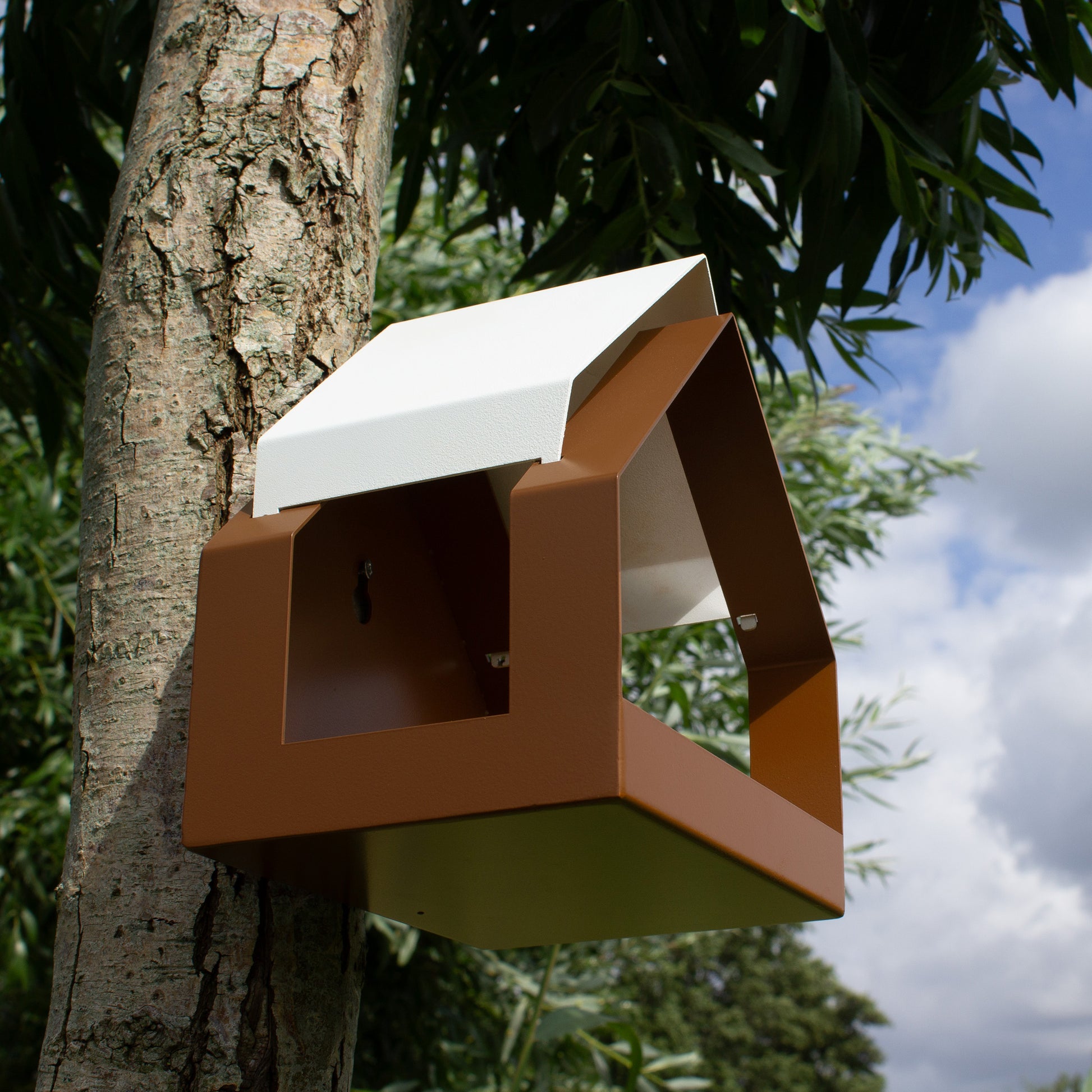 Onderaanzicht schuin van Birdfeeder the Barn aan boom met wolkenlucht op achtergrond