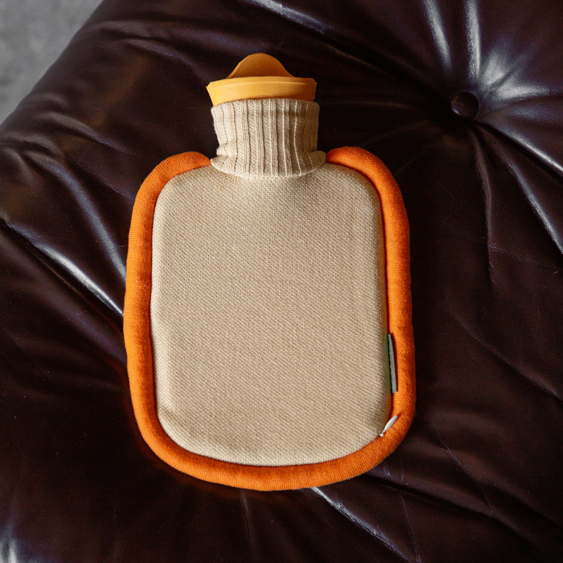 Warmwaterkruik Mini Bumper Clementine van Suite702 liggen op leren hocker