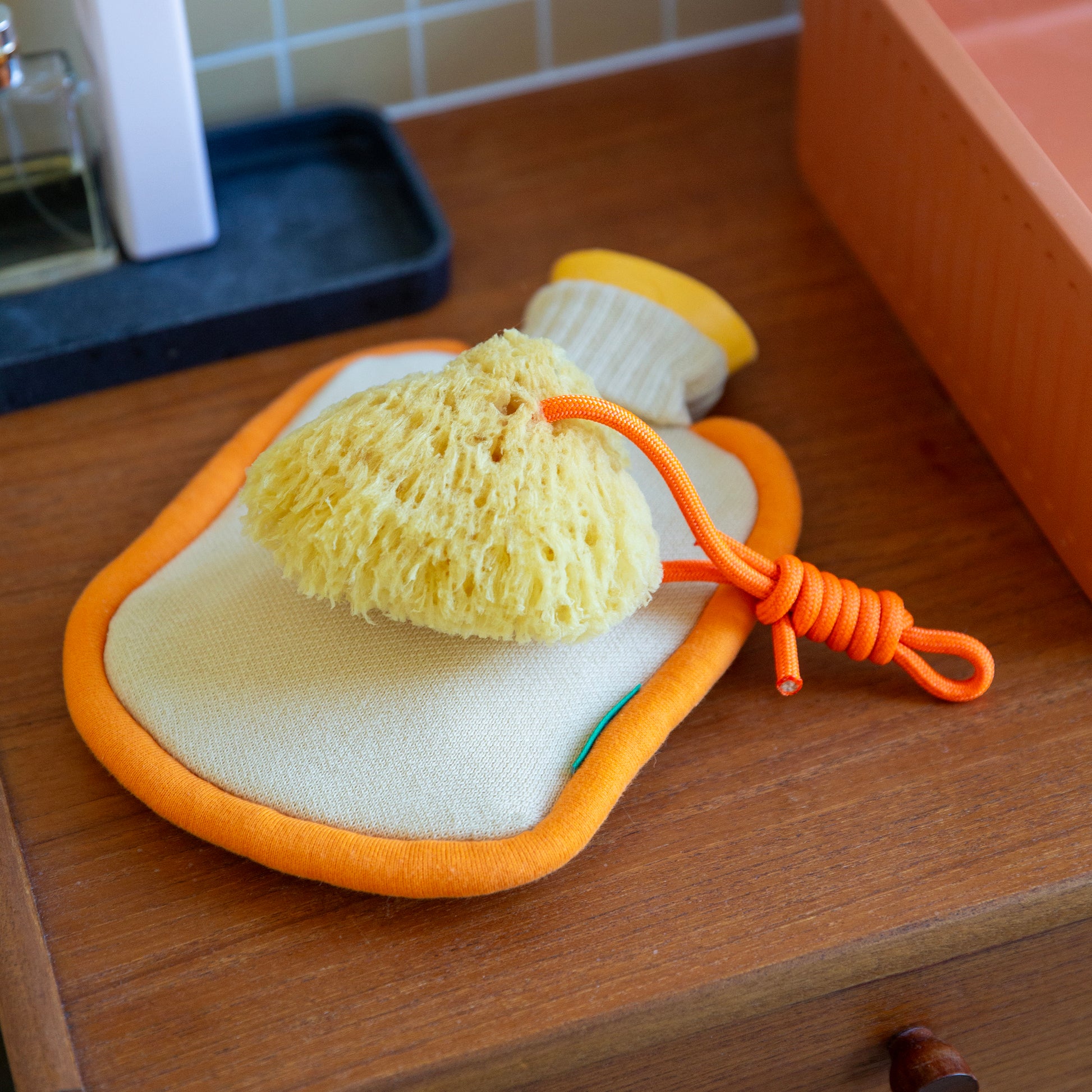 Warmwaterkruik Mini Bumper Clementine van Suite702 op houten badkamermeubel met spons