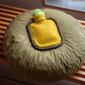 Warmwaterkruik Mini Bumper Mustard van Suite702  ligt op rond kussen 