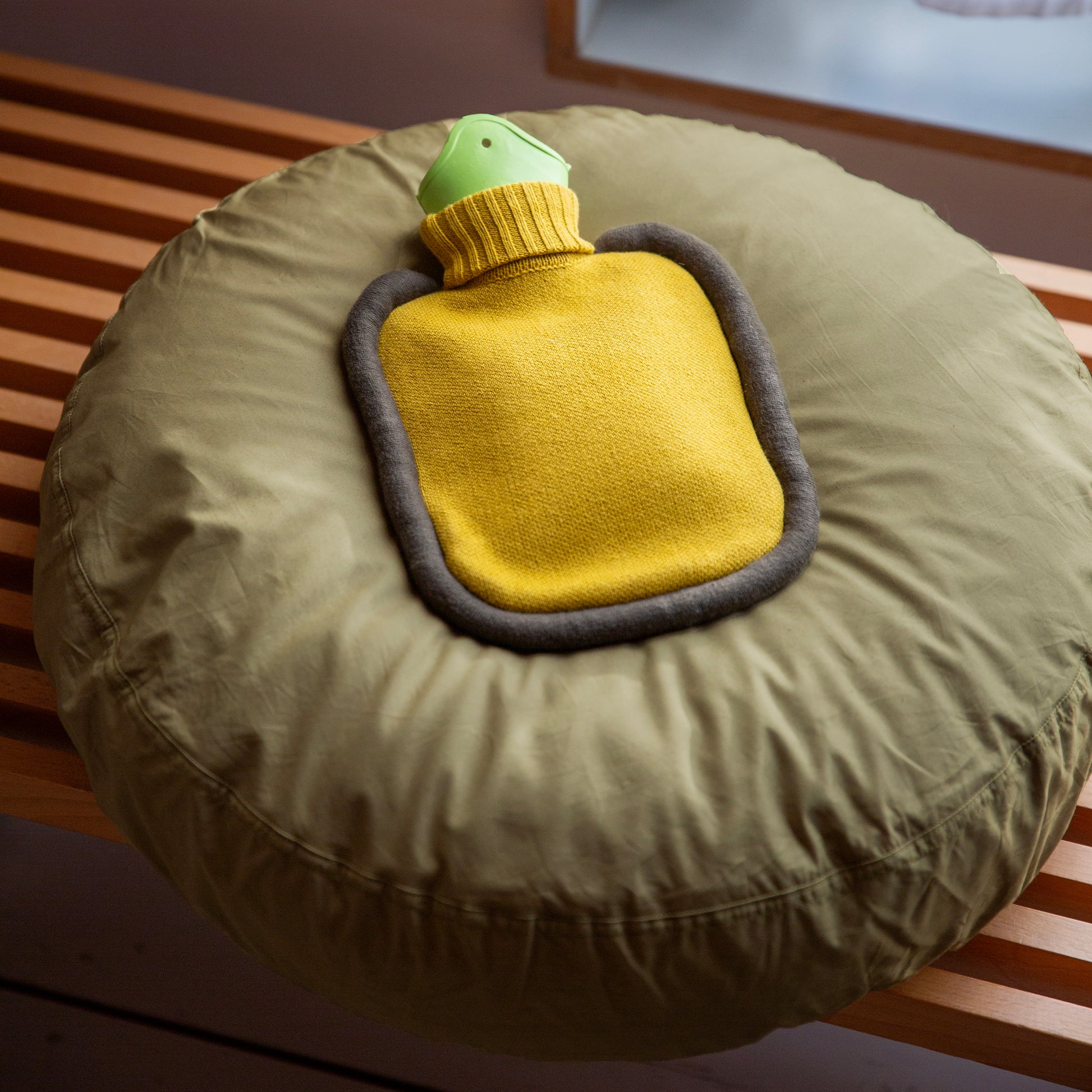 Warmwaterkruik Mini Bumper Mustard van Suite702  ligt op rond kussen 