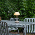 Humble Bug Oplaadbare tafellamp Frosted Beige│op metalen buitentafel met licht aan│art. HUMTL00305