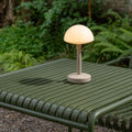 Humble Bug Oplaadbare tafellamp Frosted Beige│voorkant met witte achtergrond│art. HUMTL00305op groen buitentafel met licht aan