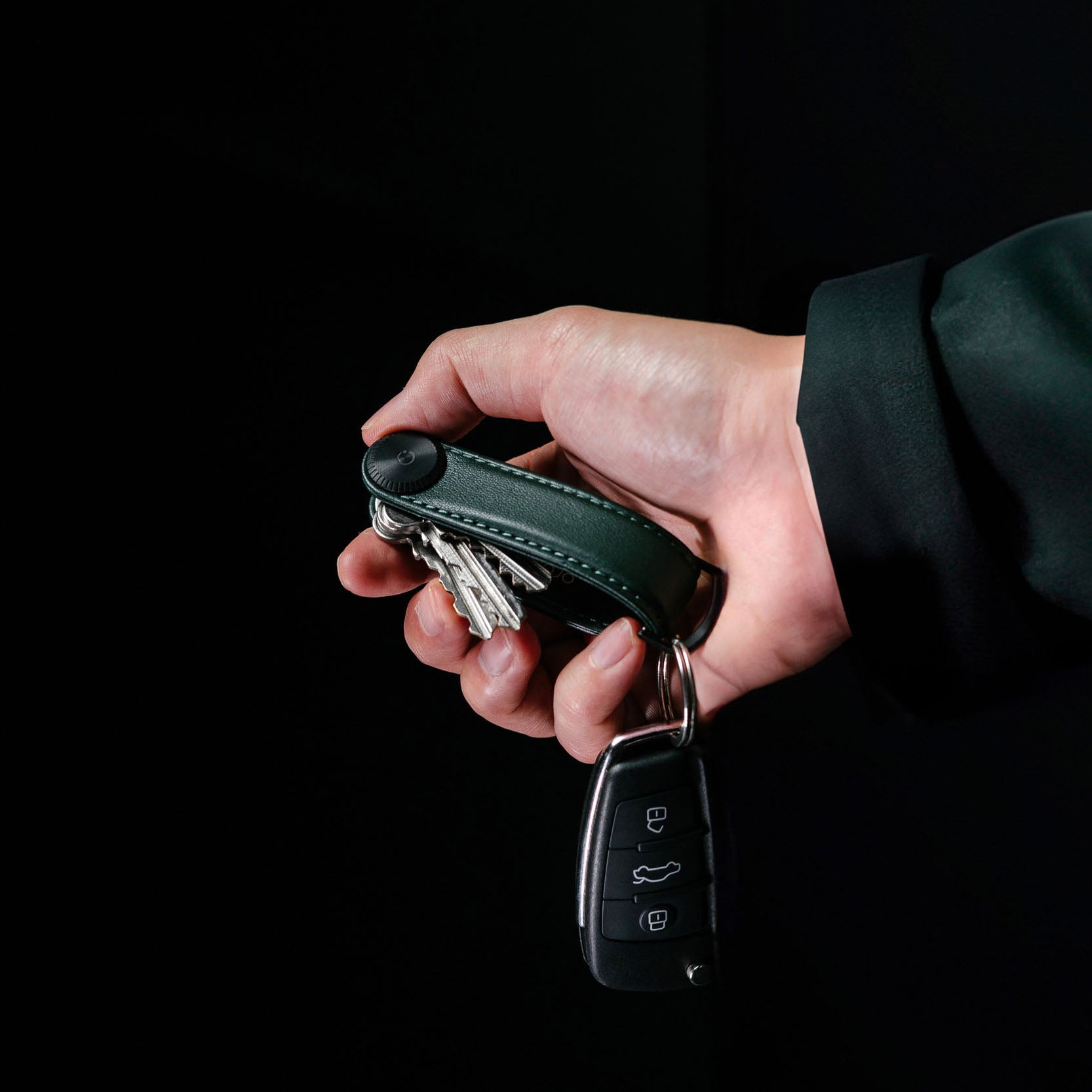 Orbitkey Sleutelhouder Pro Blackout│Key Organiser│art. KPR1-BKT-101│in hand vastgehouden met autosleutel en zwarte achtergrond