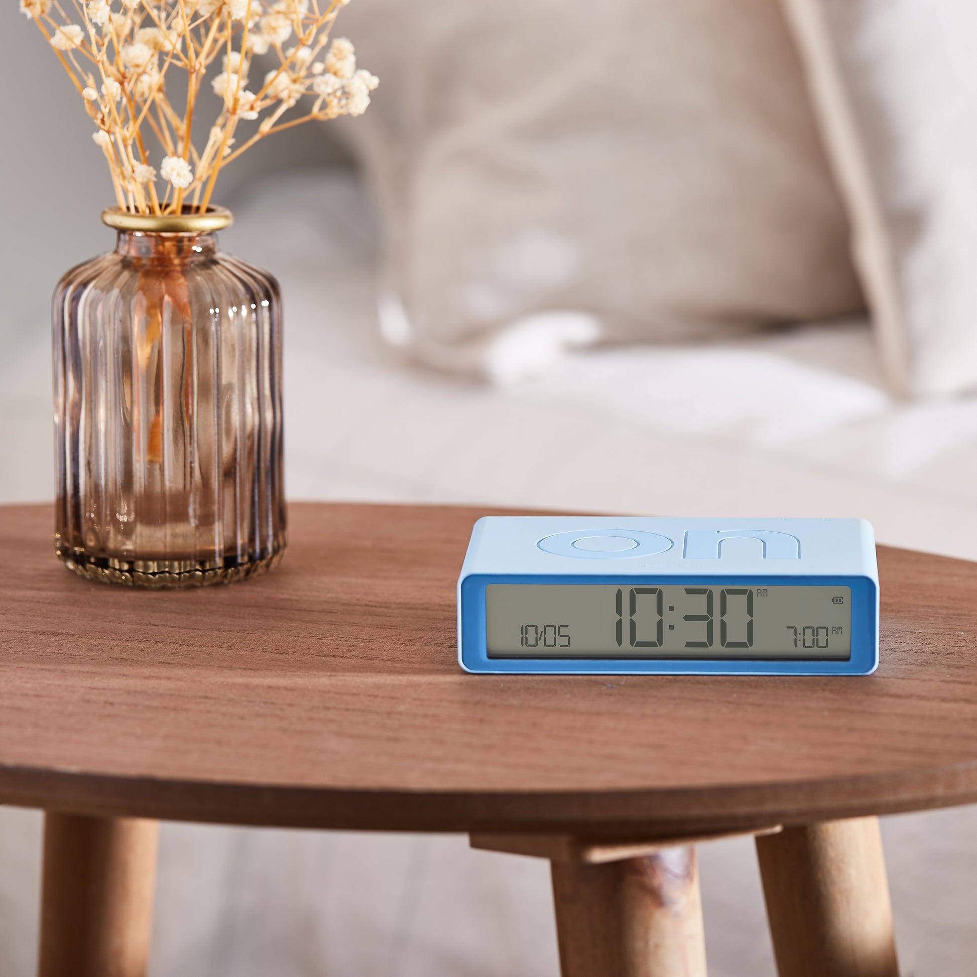 Lexon Flip+ Wekker Digitaal Lichtblauw│art. LR157LB1│vooraanzicht op rond houten tafeltje