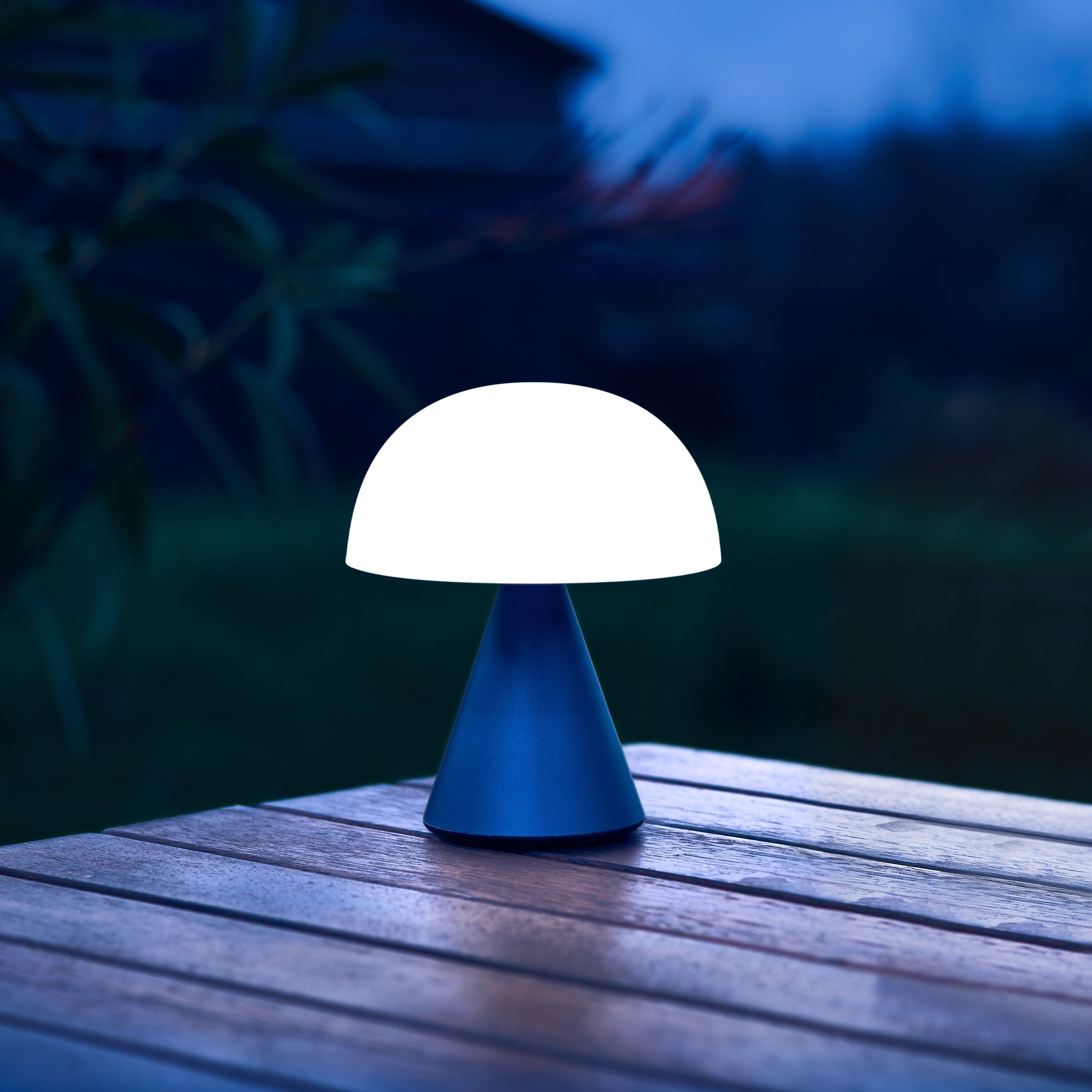Lexon Mina Medium Donkerblauw│Oplaadbare LED-lamp│art. LH64MDB│op buitentafel met wit licht aan