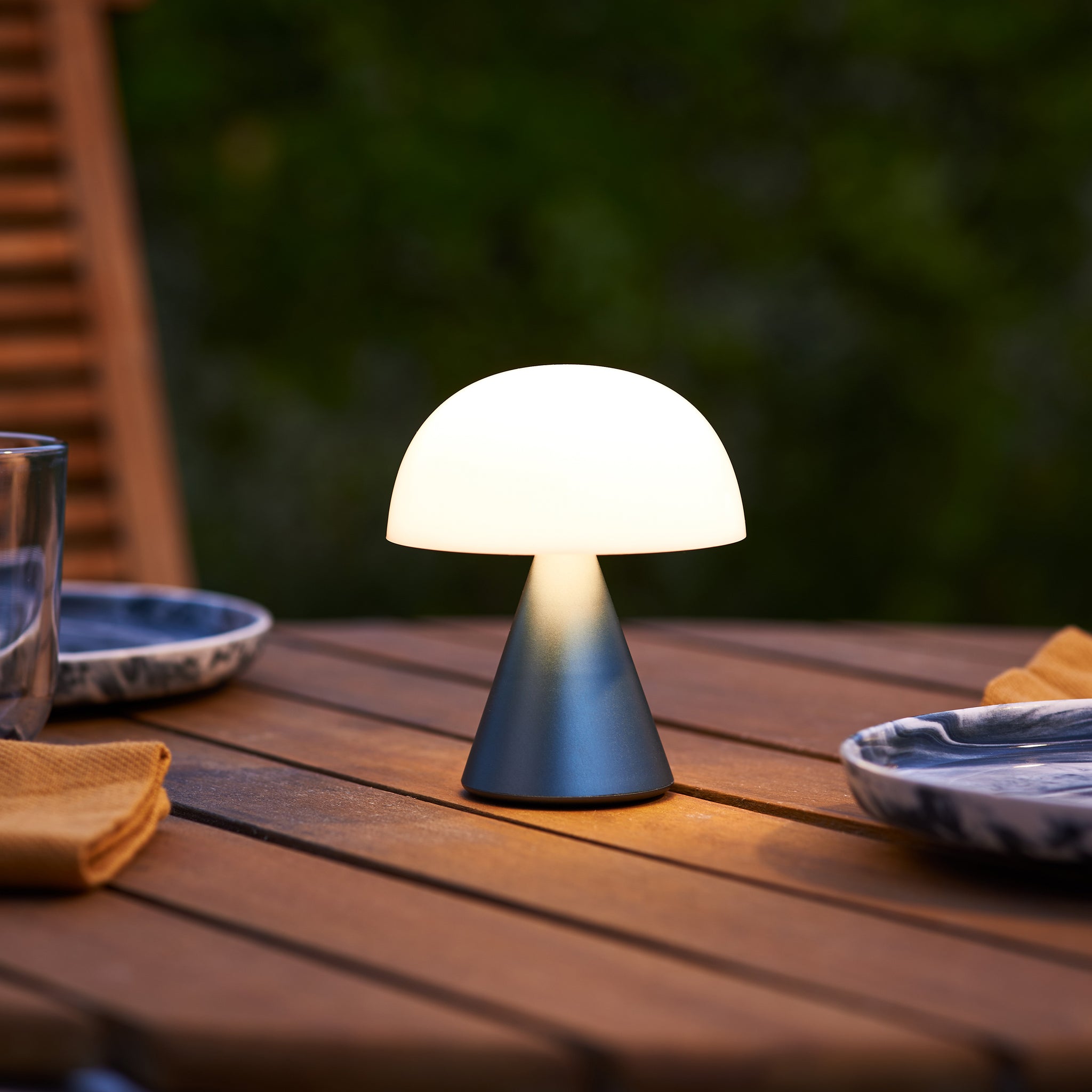 Lexon Mina Medium Donkerblauw│Oplaadbare LED-lamp│art. LH64MDB│op buitentafel naast blauwe borden