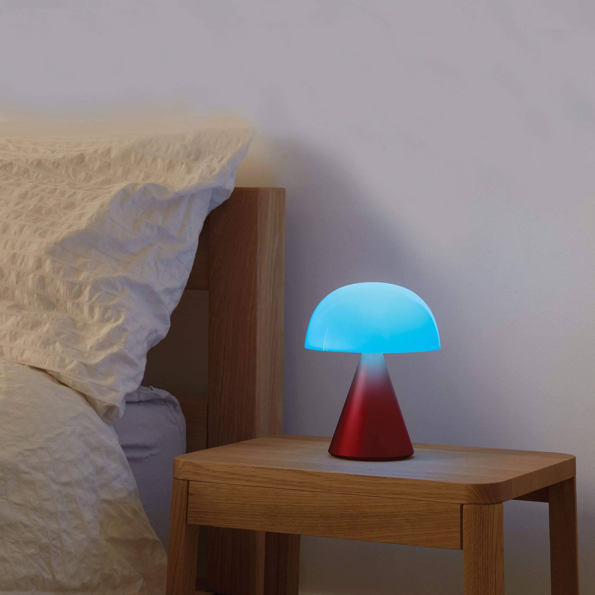 Lexon Mina Large Oplaadbare Tafellamp Donkerrood│art. LH65DR│op nachtkastje met blauw licht aan