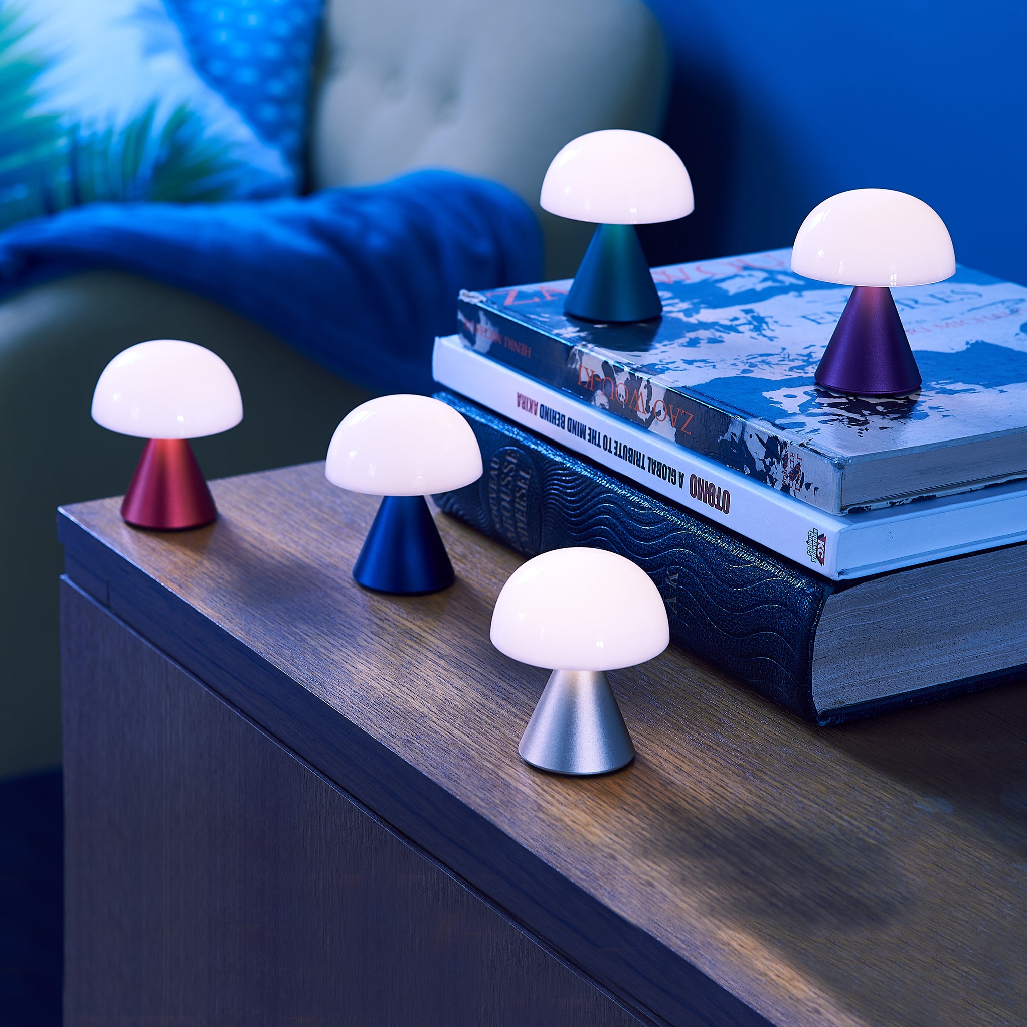 Lexon Mina Small Donkerblauw│Oplaadbare LED-Lamp│art. LH60MDB│groep op houten kastje in donker met lampjes aan