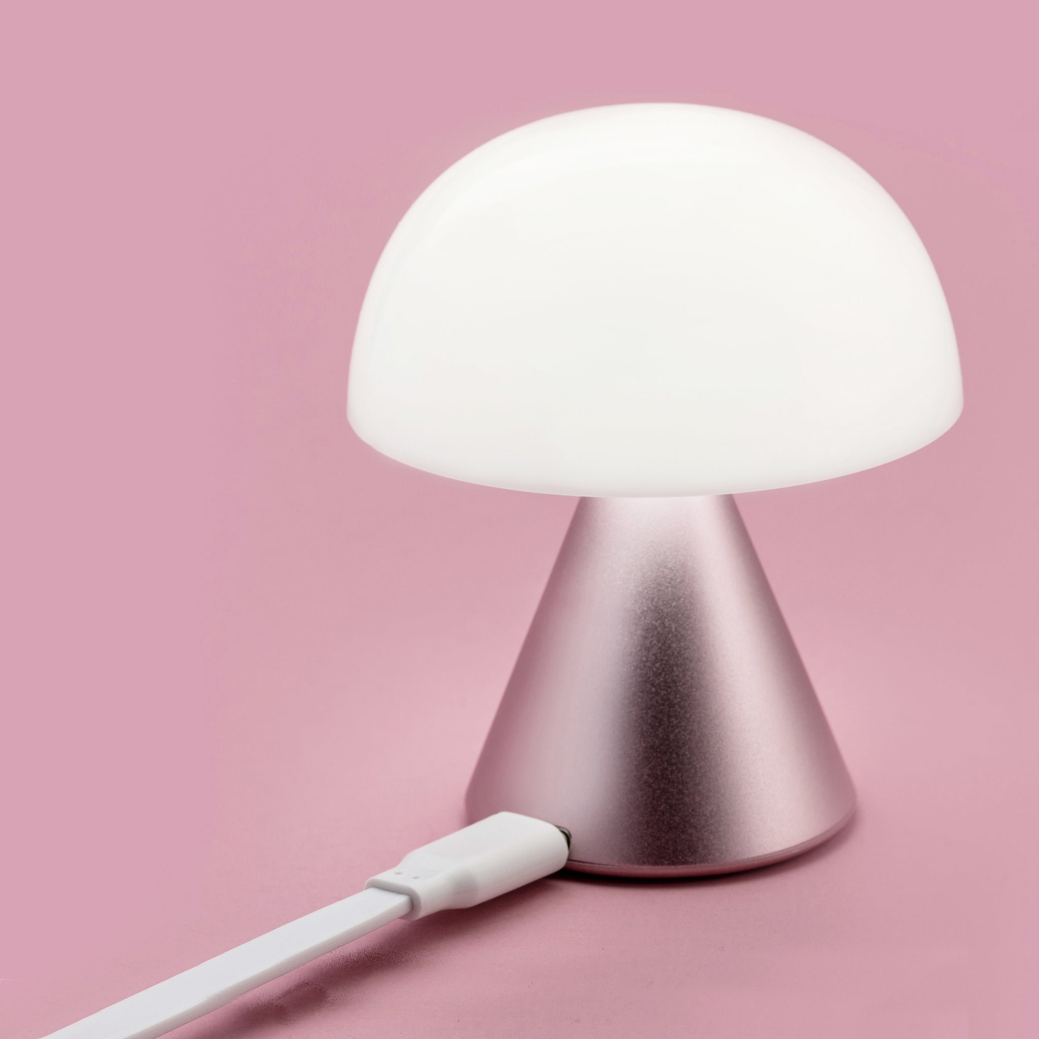 Lexon Mina Small Roze│Oplaadbare LED lamp│art. LH60MLP│wit licht aan met roze achtergrond en usb-kabel